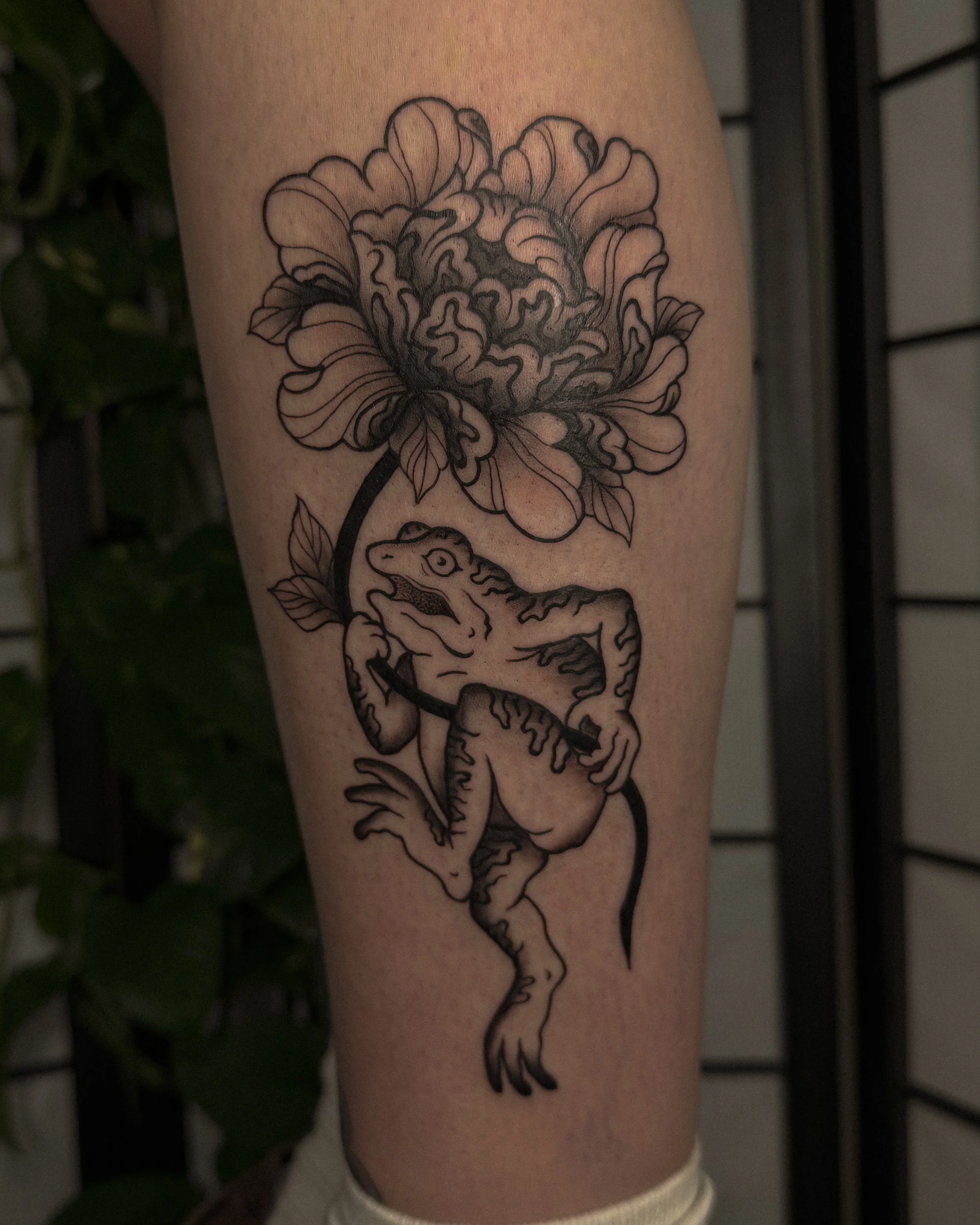 Tattoo of a dragon and a large peony flower on a person's arm.