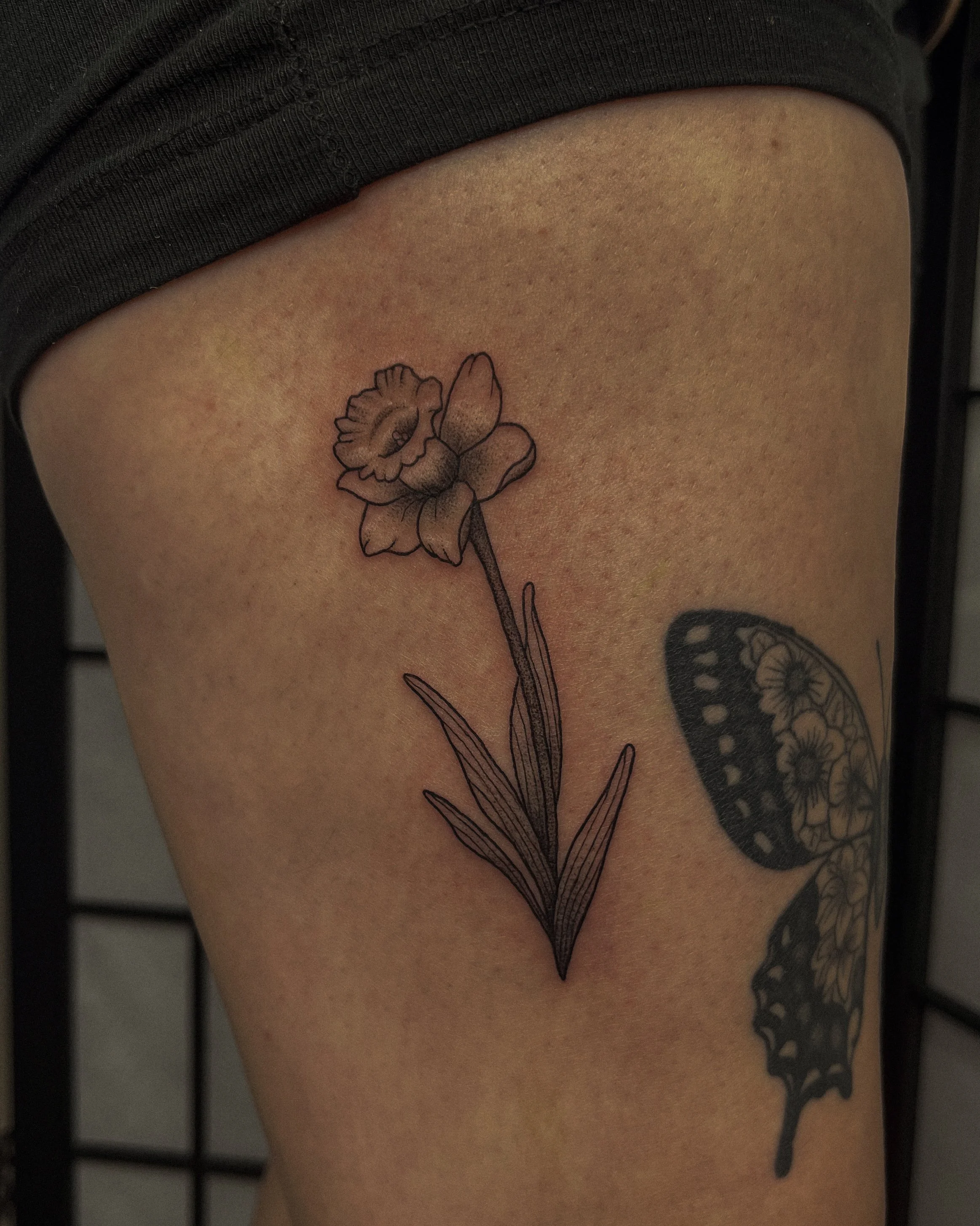 Black and white line drawing of a flower tattoo on person's skin.