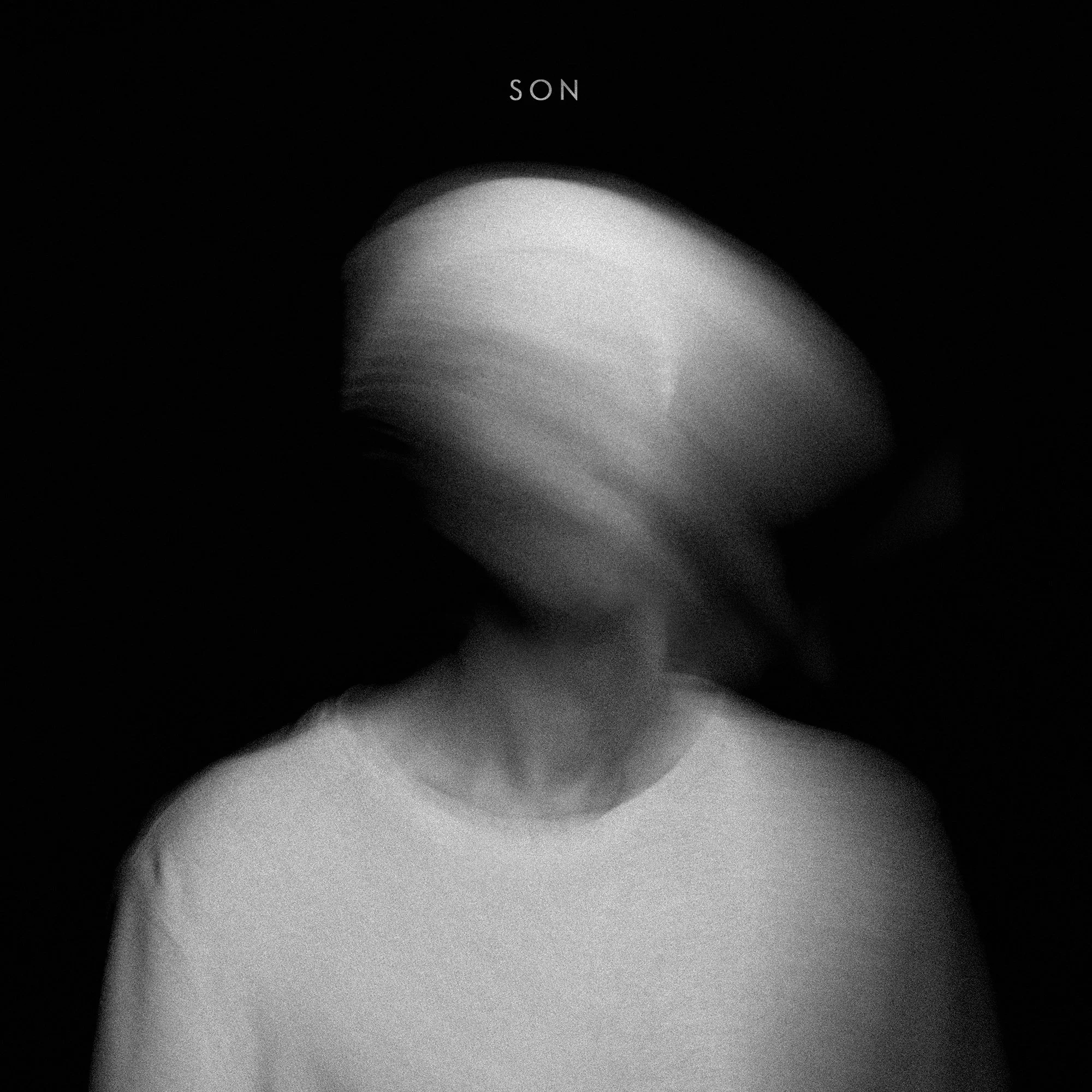 Blurred black and white photo of a person with their head moving quickly, wearing a light-colored shirt, against a dark background with the word 'SON' at the top.