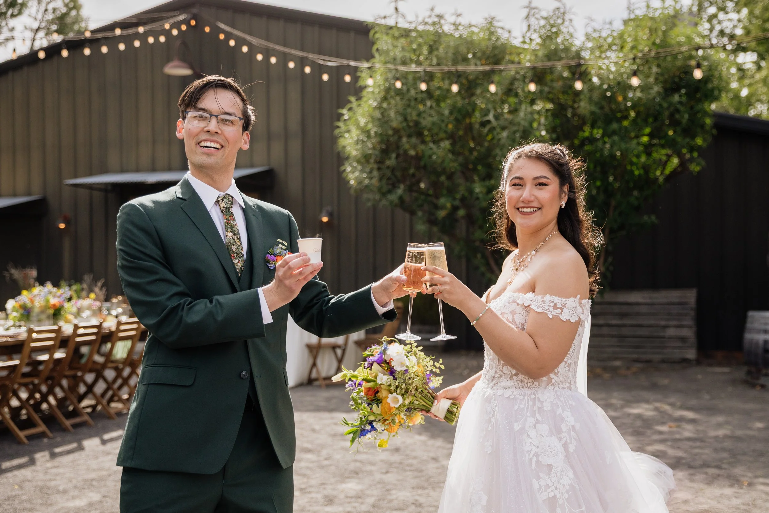Bride and groom toasting during their wedding reception while holding seasonal flowers at a Sonoma County wedding.