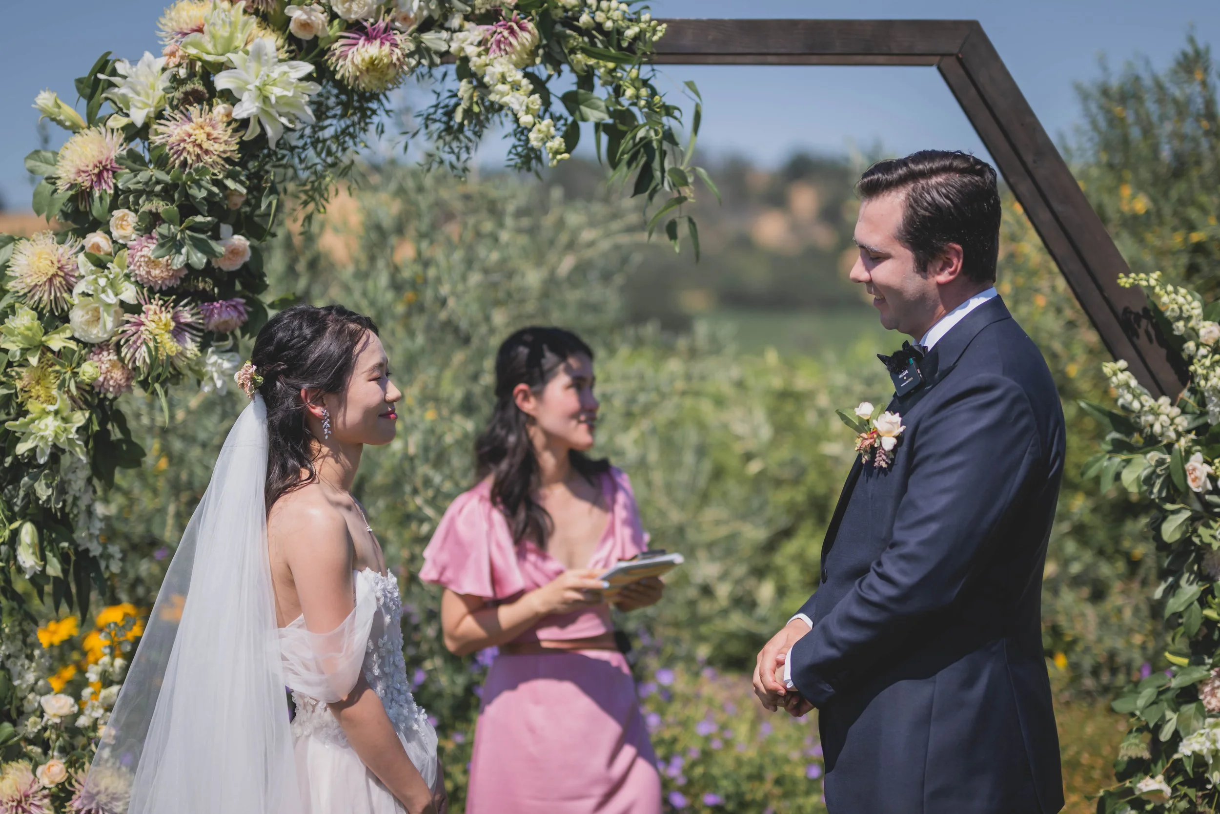 Saying I do under a hexagon arch with live floral installments