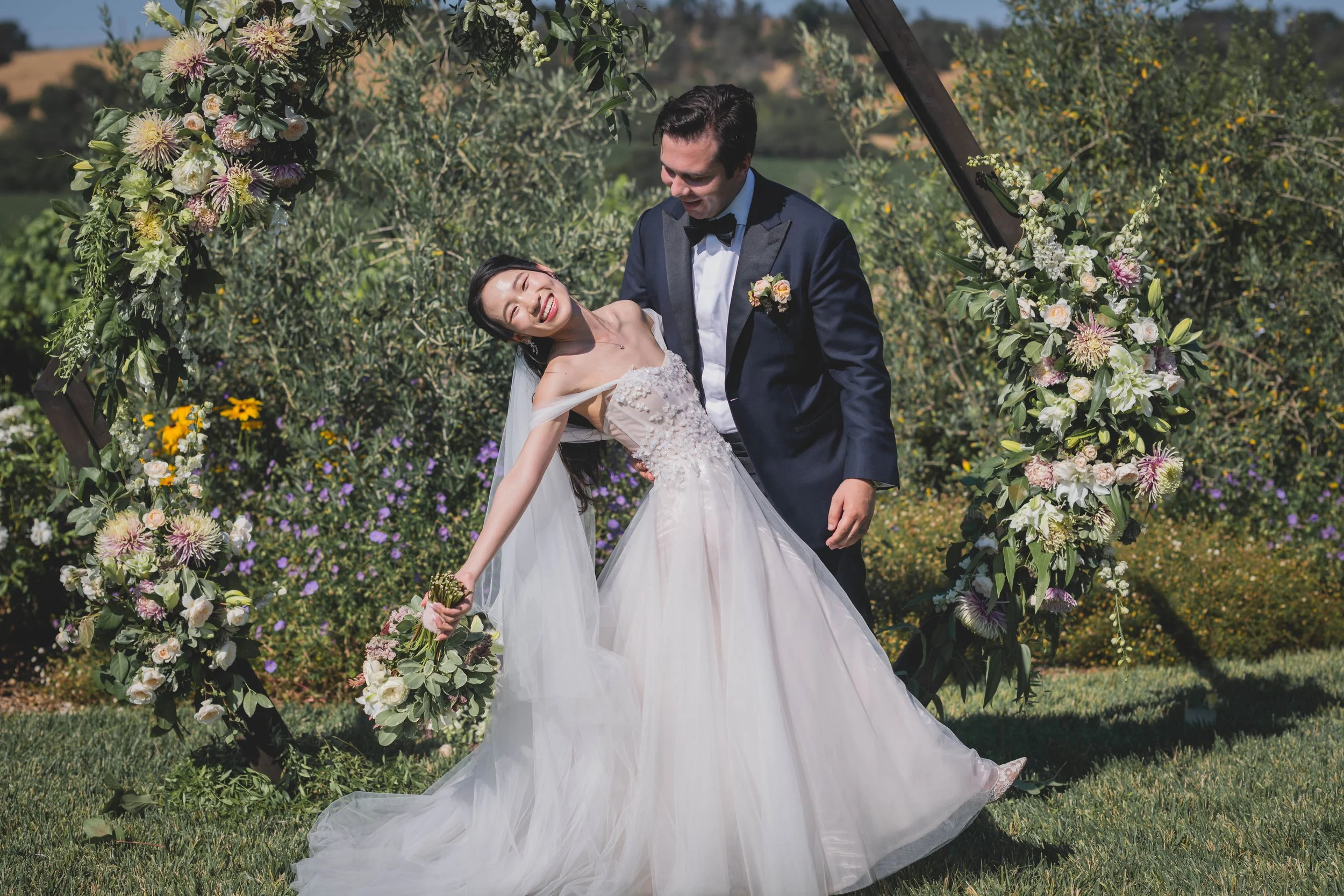 Sonoma county bride holding a stunning bouquet with husband supporting her as she falls back in his arms
