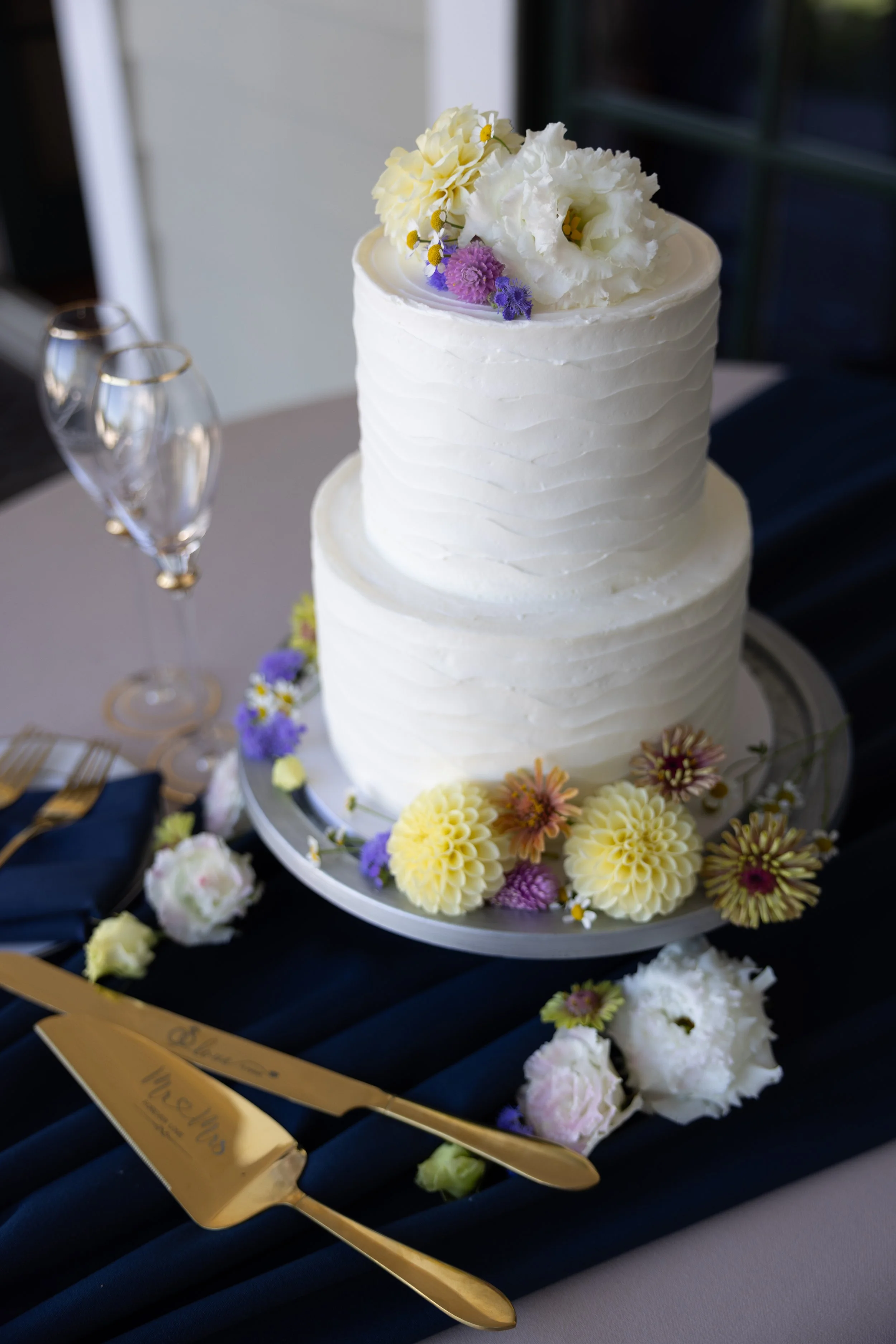 Simple white wedding cake adorned with fresh local flowers