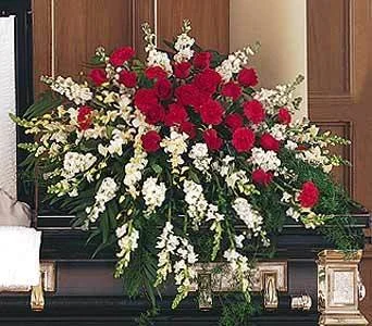 Large floral arrangement of red and white flowers on a black piano in a room with wood-paneled walls.
