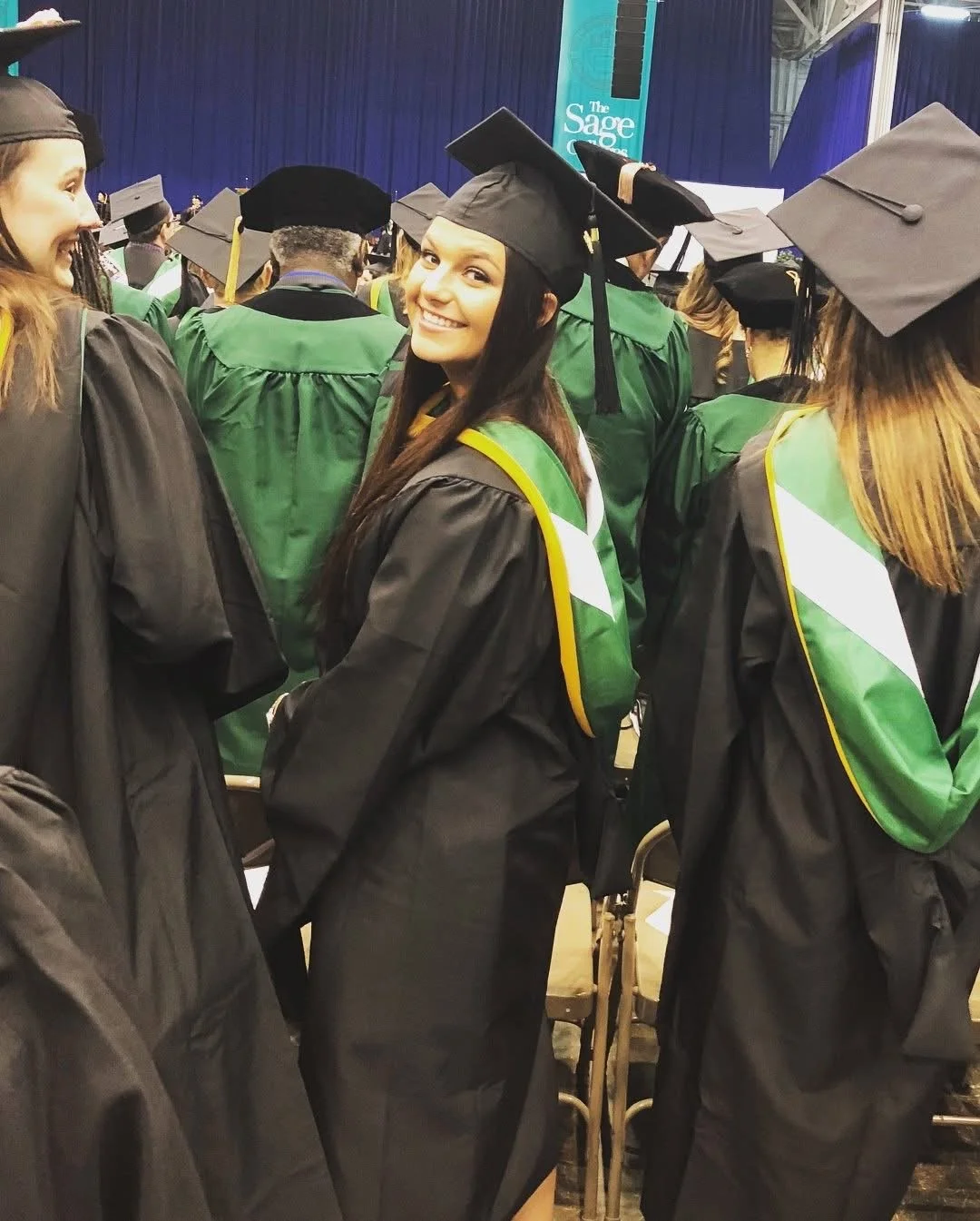 Megan's graduation - a smiling photo of a new OT in her graduation gown and cap.
