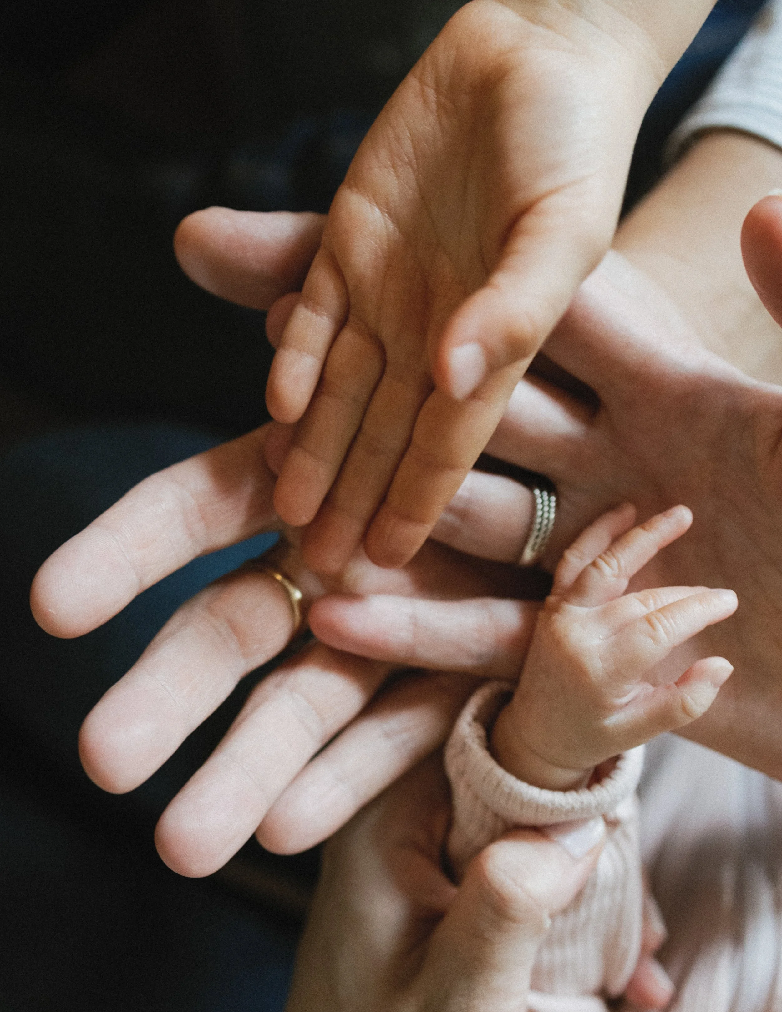 Hands of different sizes stacked together, symbolizing family and connection.