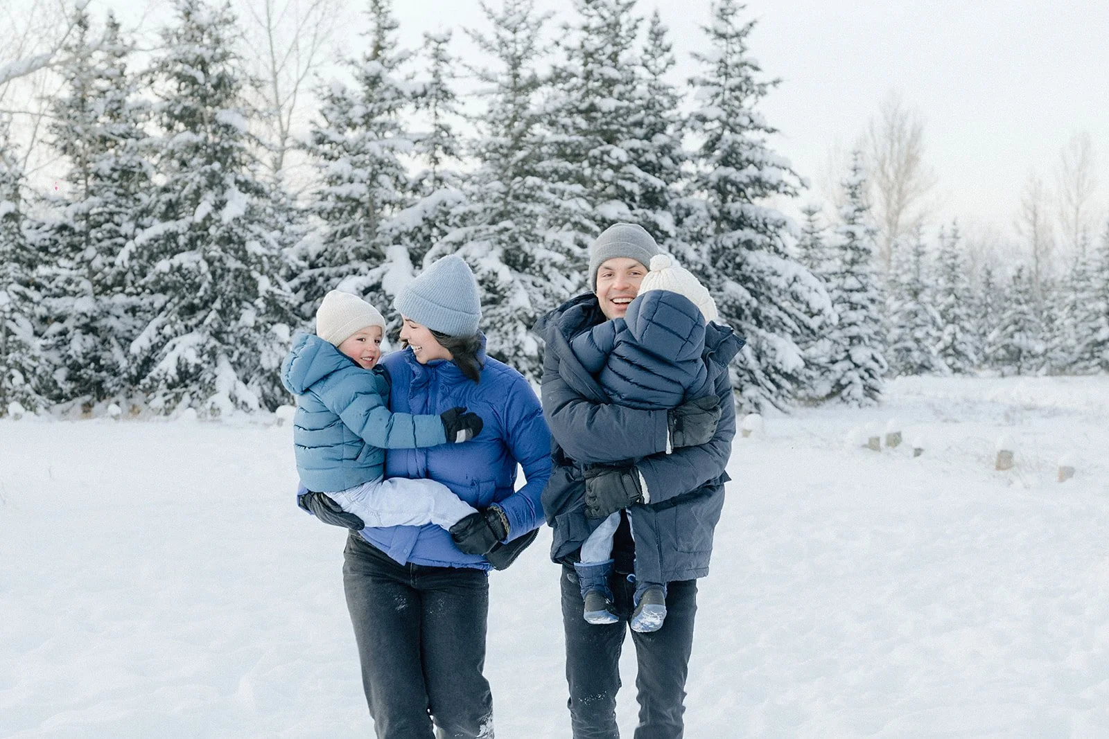 Family wearing winter clothes smiling in snowy forest