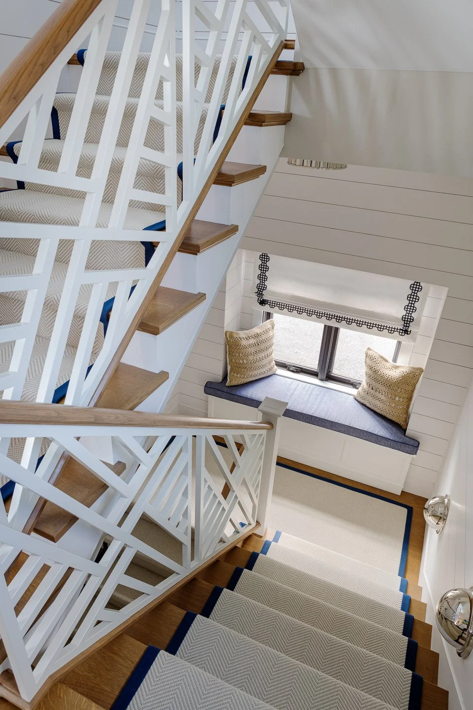 A sculptural staircase designed by Lindsey Architects, blending custom geometric railing detailing, warm natural wood treads, and bright coastal-inspired interiors. The layered stair composition creates a dramatic architectural focal point while rein