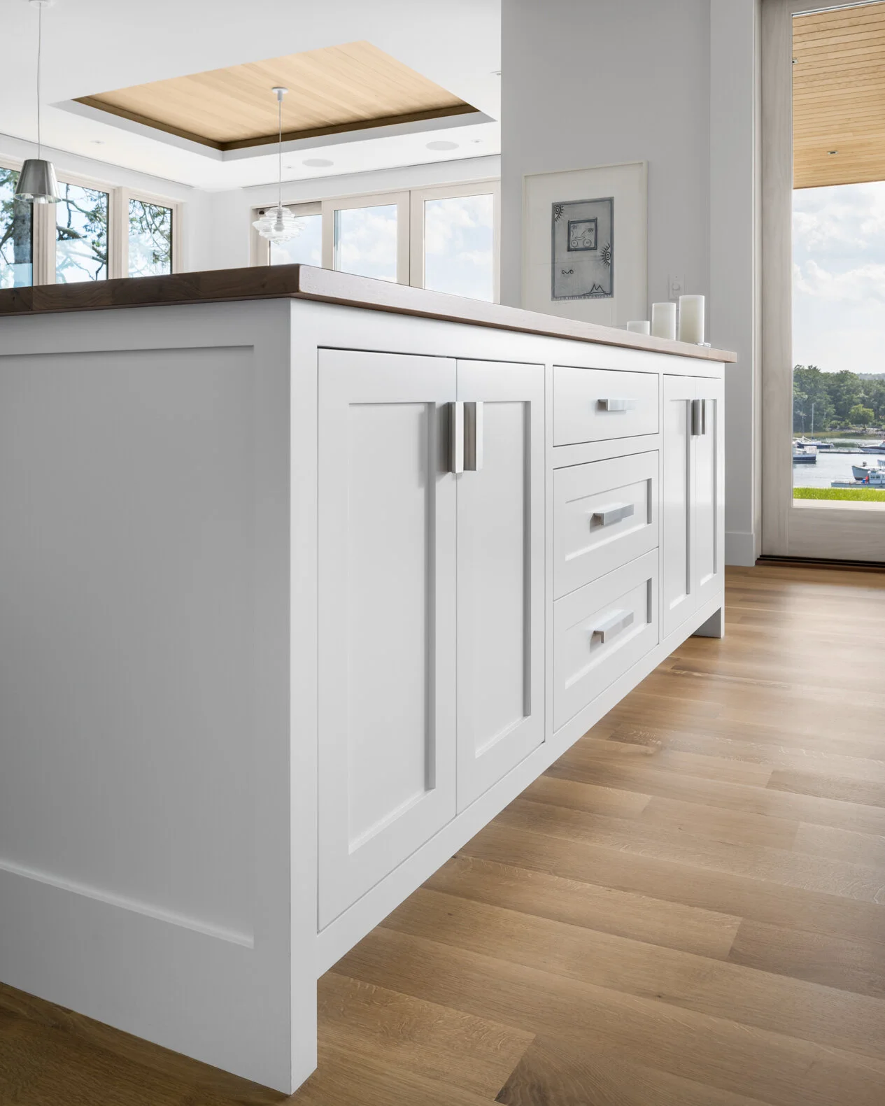 A refined kitchen detail designed by Lindsey Architects, showcasing custom cabinetry, warm natural wood flooring, and clean contemporary detailing inspired by modern New England coastal architecture. Carefully proportioned millwork, soft natural ligh