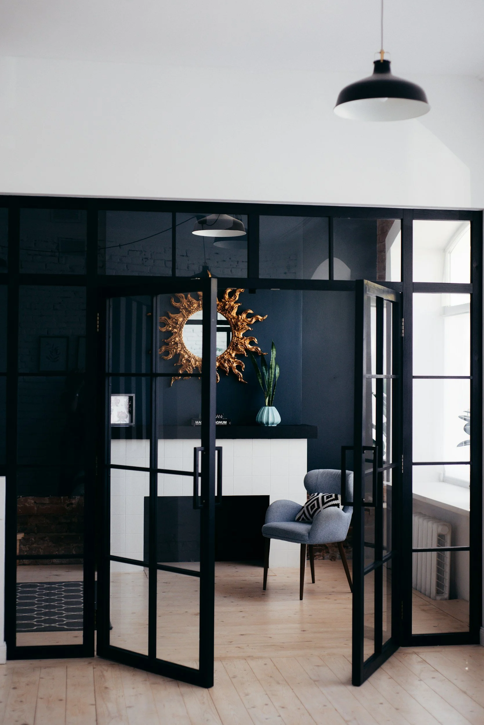 Black steel-framed glass partition doors opening into a flexible home office, designed by Lindsey Architects in Rye, New Hampshire.