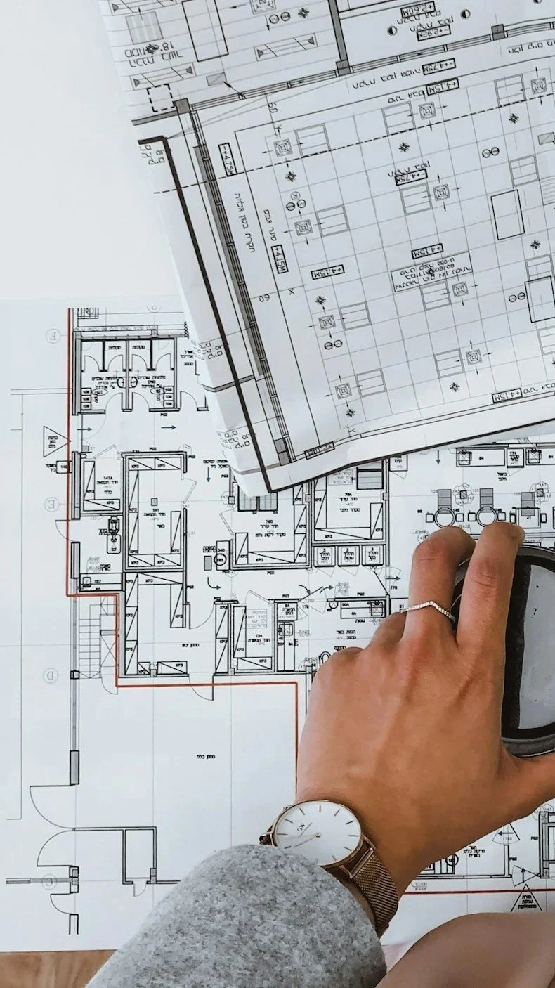 Architect reviewing detailed floor plan drawings for a hillside home with reverse floor plan layout — custom residential architecture by Lindsey Architects, serving Maine, NH, and the New England seacoast.