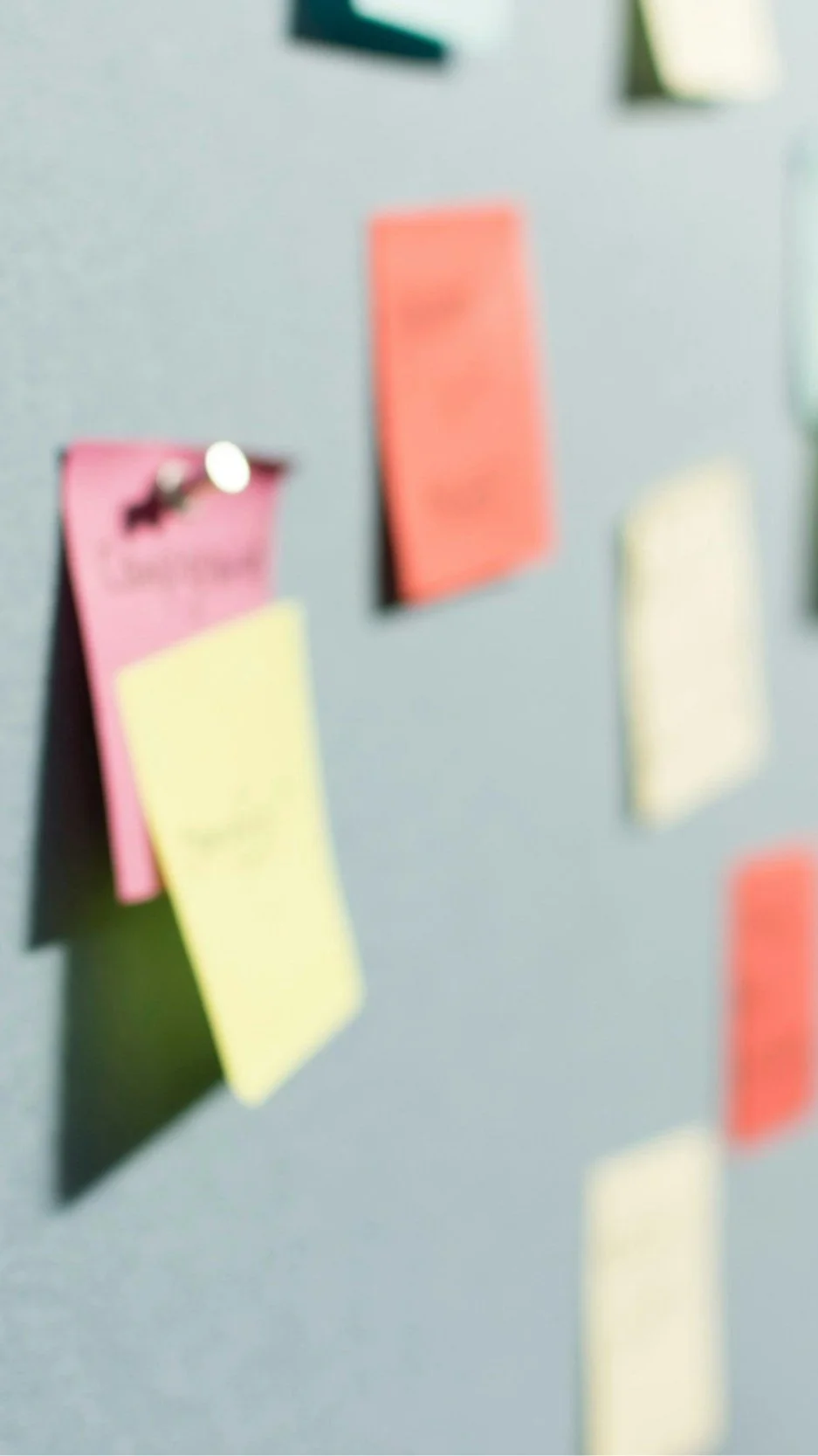 Soft-focus colorful sticky notes pinned to a board — illustrating the planning and feasibility stage where Lindsey Architects weighs site conditions, building codes, and structural factors in custom coastal New England home design.