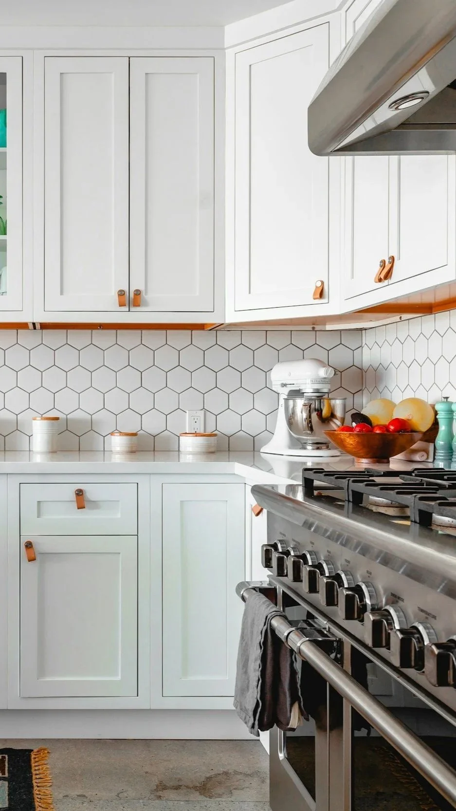 White shaker cabinet kitchen with hexagonal tile backsplash, professional range, and leather-pull hardware — illustrating the multi-functional custom kitchen design Lindsey Architects creates for coastal homes in Portsmouth, New Hampshire.