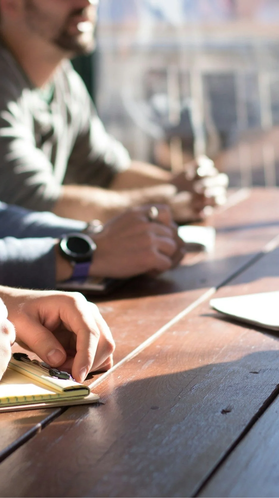 People collaborating at a table during a project meeting, illustrating the architect-builder collaboration central to the Lindsey Architects process.