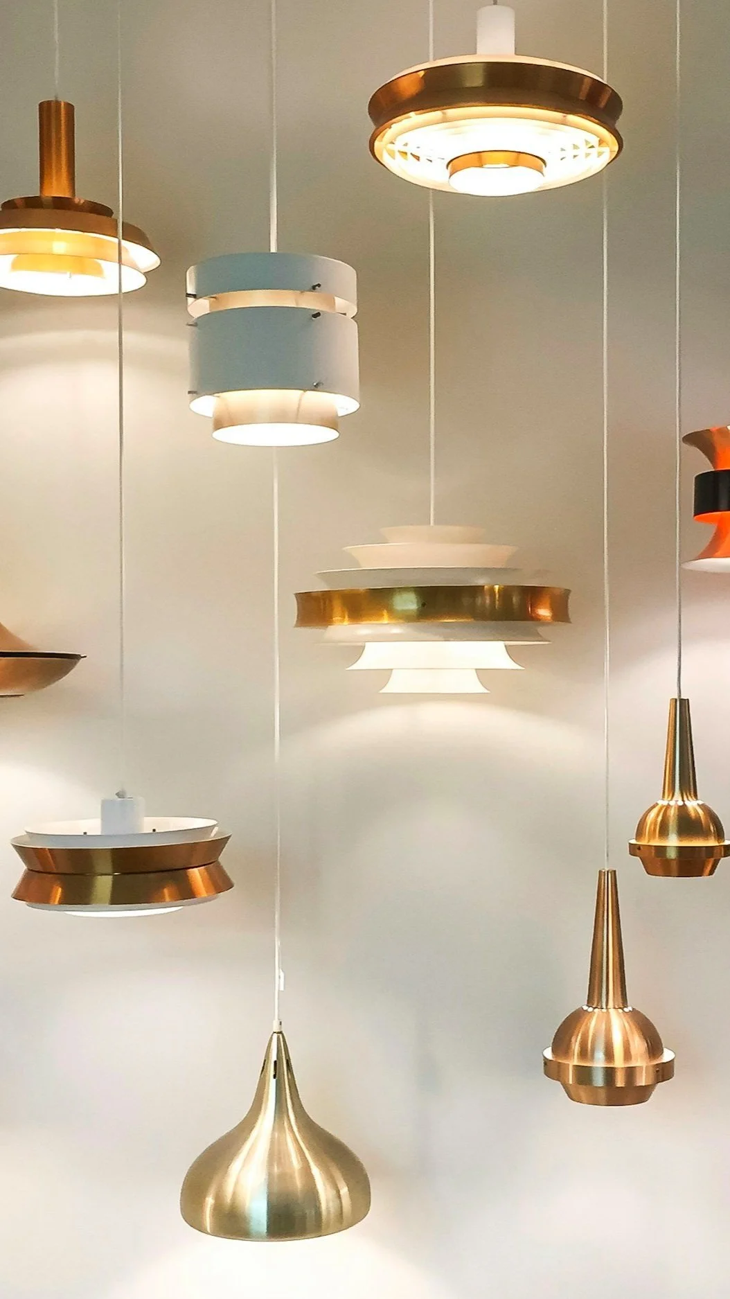 A grouping of solid brass and copper mid-century-style pendant lights — illustrating the high-quality fixtures and finishes Lindsey Architects specifies for lasting beauty and performance in custom Seacoast New England homes.