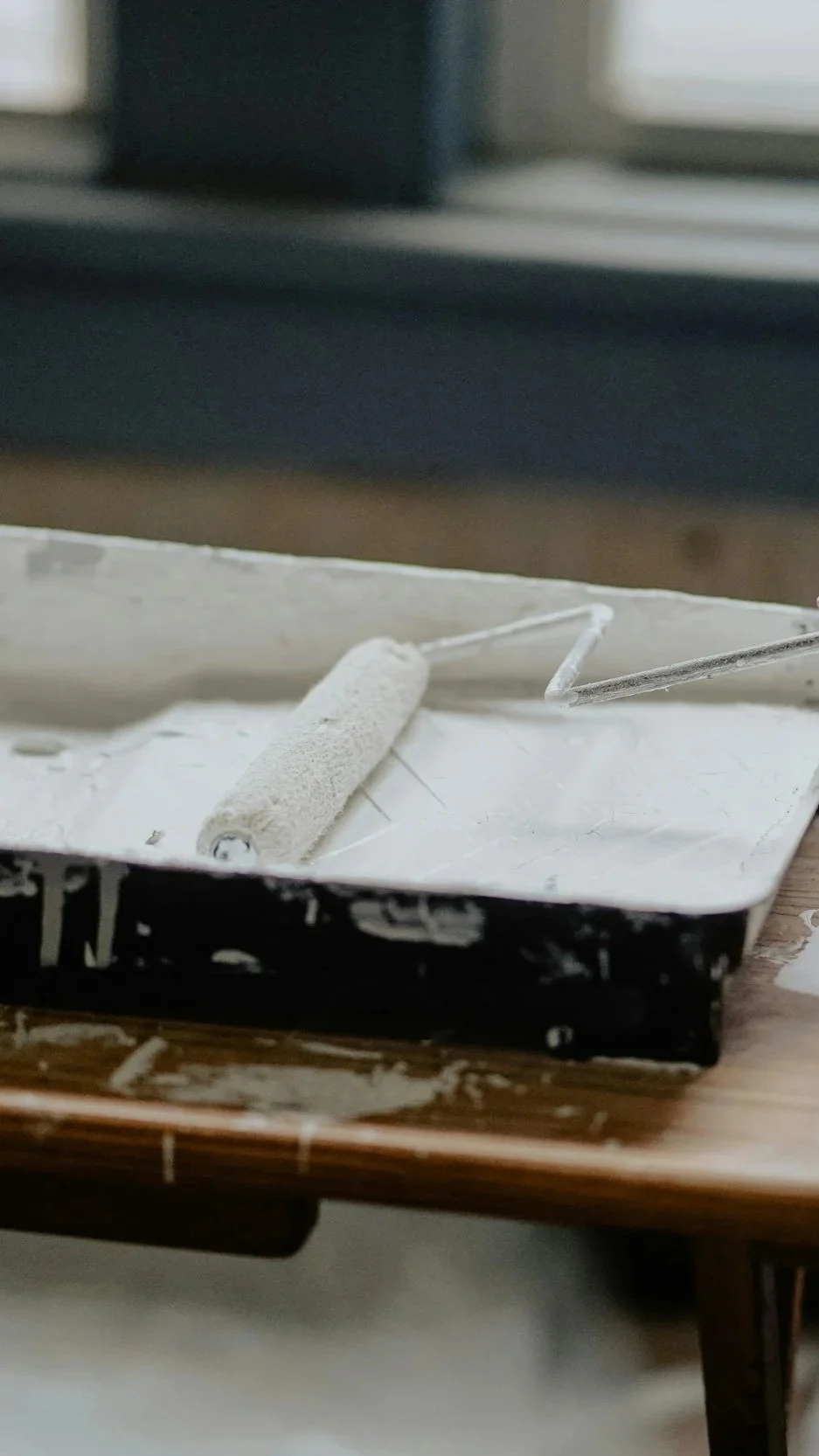 Close-up of a paint roller in a white tray during a home renovation — illustrating the thoughtful updating and juxtaposition of old and new that Lindsey Architects guides in coastal Maine home renovations.