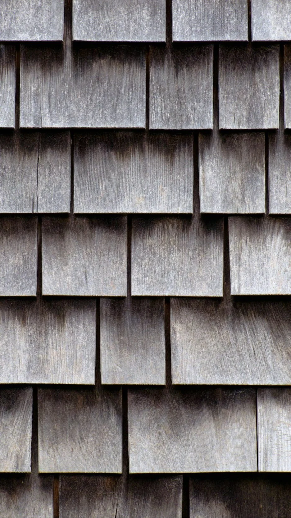Close-up of weathered gray cedar shake shingle siding, a durable coastal material used by Lindsey Architects in Rye NH