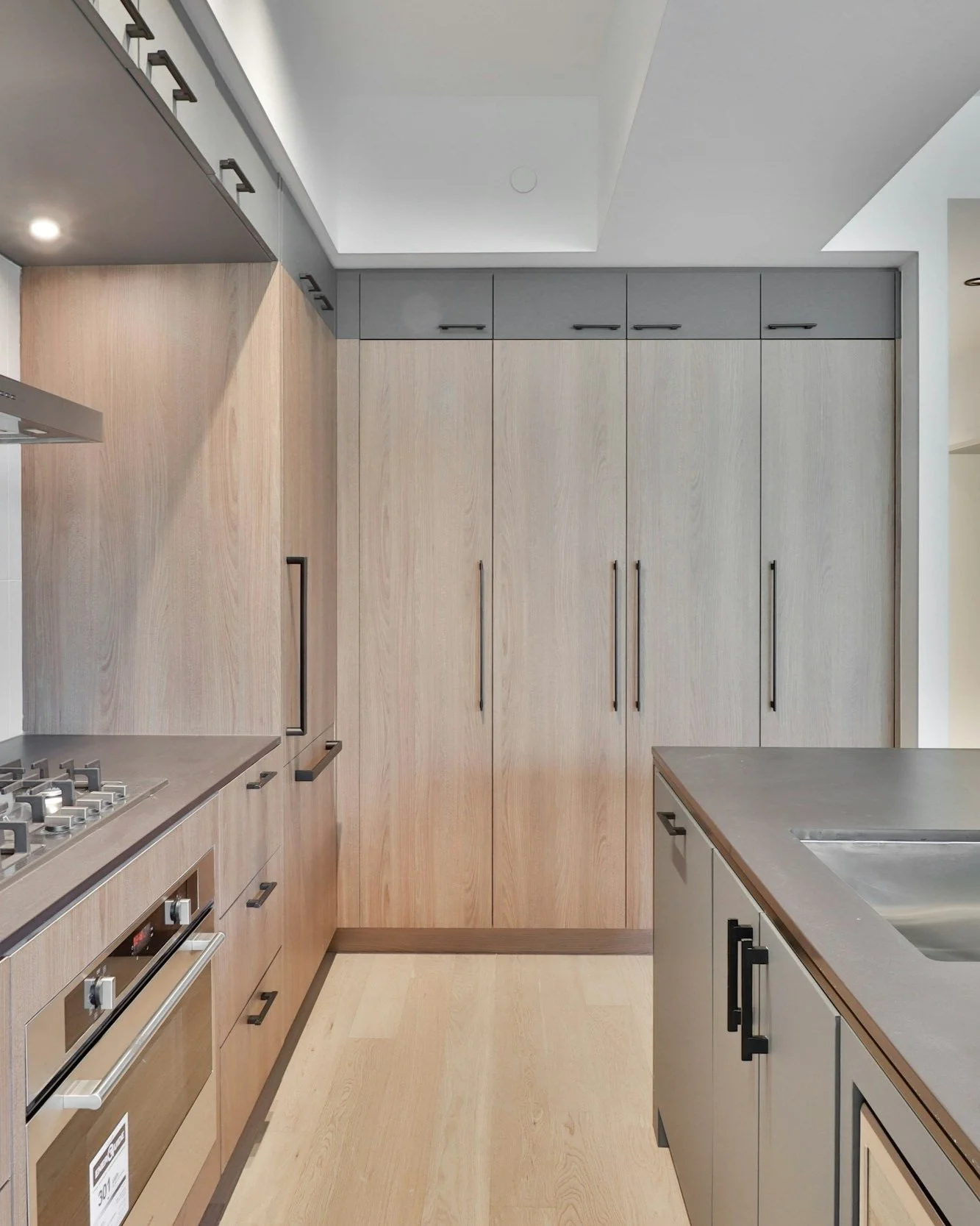 Modern custom kitchen with light wood cabinetry, integrated appliances, and a gas cooktop designed by Lindsey Architects in York, Maine.