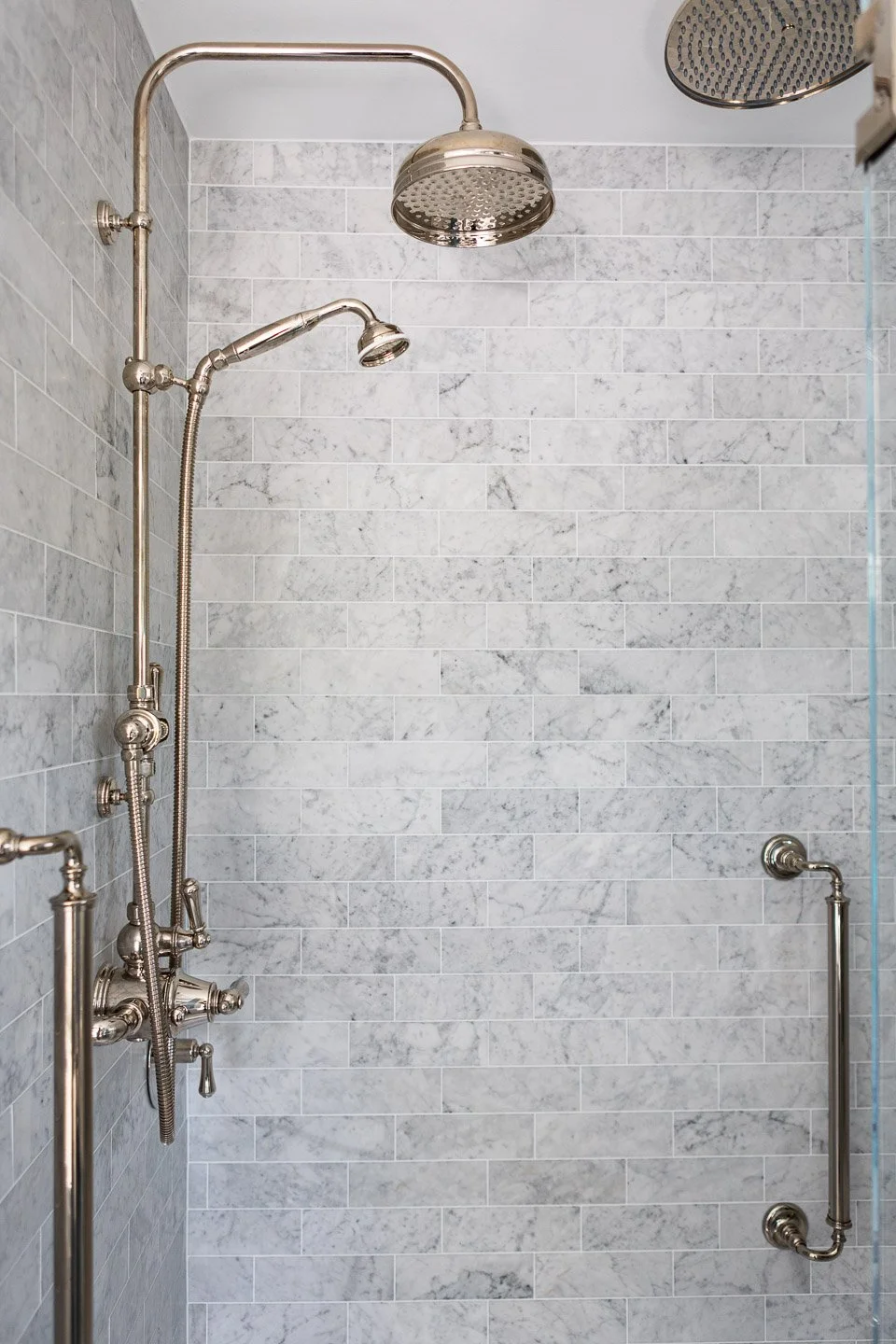 A spa-inspired shower designed by Lindsey Architects, featuring timeless marble tile, polished nickel fixtures, and refined contemporary detailing tailored for luxury coastal living. Clean architectural lines, soft natural textures, and carefully sel