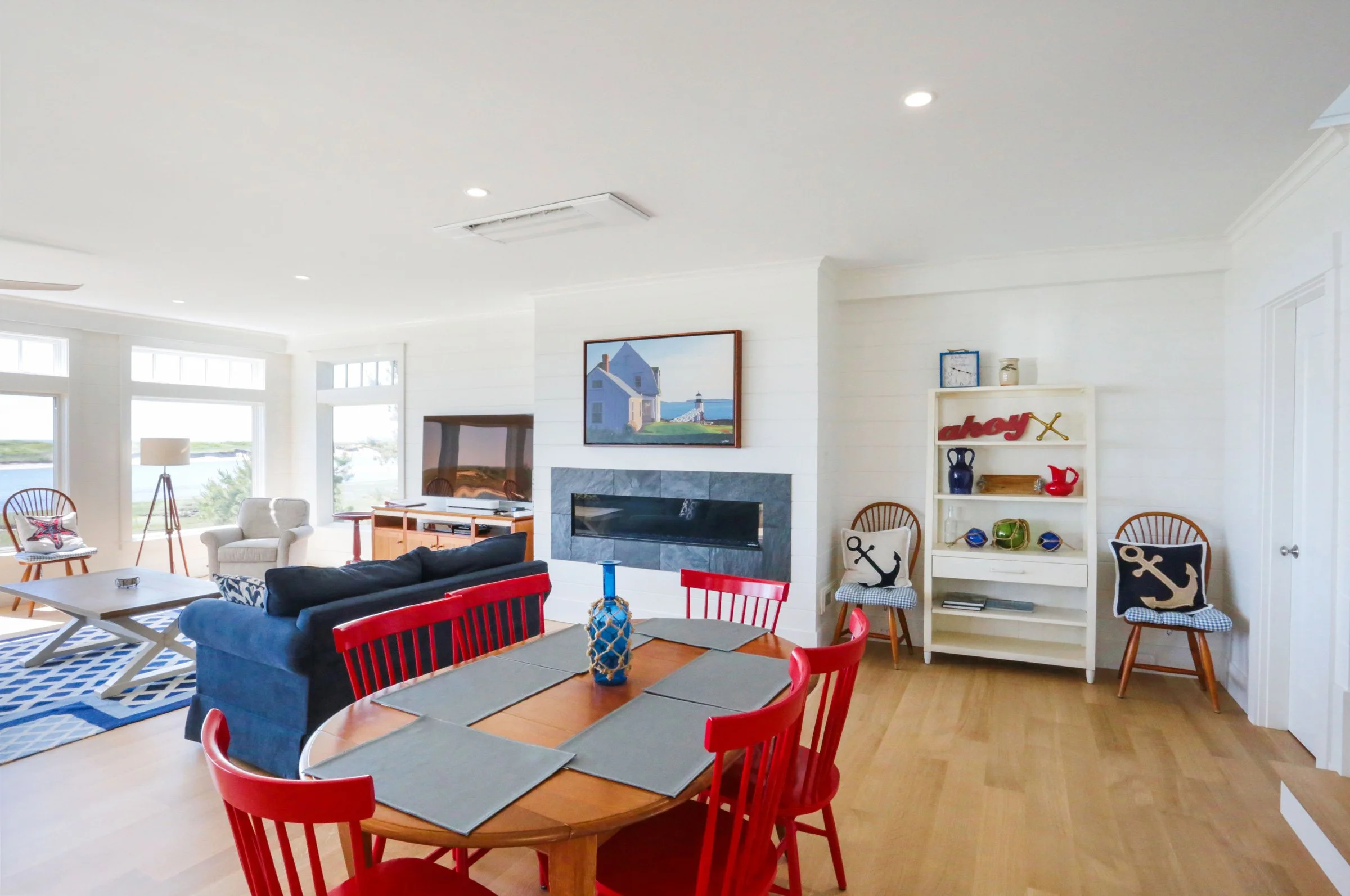 A bright and inviting waterfront living and dining space designed by Lindsey Architects, featuring open-concept coastal interiors, expansive natural light, and panoramic marsh views inspired by the Maine and New Hampshire shoreline. The contemporary 