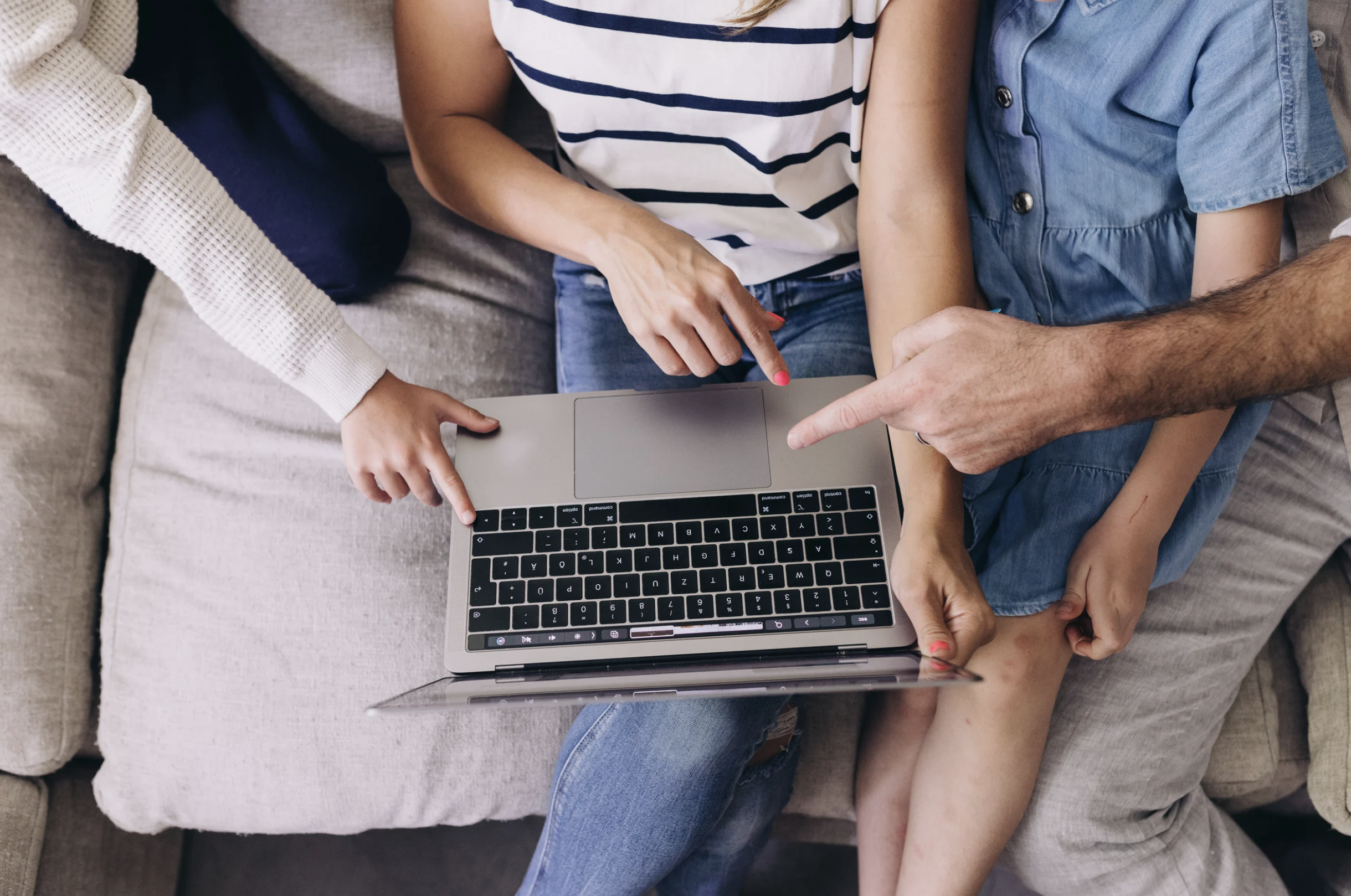 Family browsing online home plans on a laptop while considering custom home design options — Lindsey Architects explains why stock plans often fall short for site-specific coastal homes in Maine and New Hampshire.