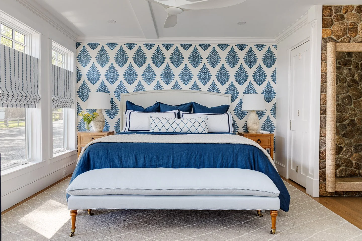 A serene coastal bedroom designed by Lindsey Architects, blending timeless New England detailing with soft contemporary interiors and natural light. Custom millwork, patterned wall coverings, and layered blue and neutral textiles create a calm and so