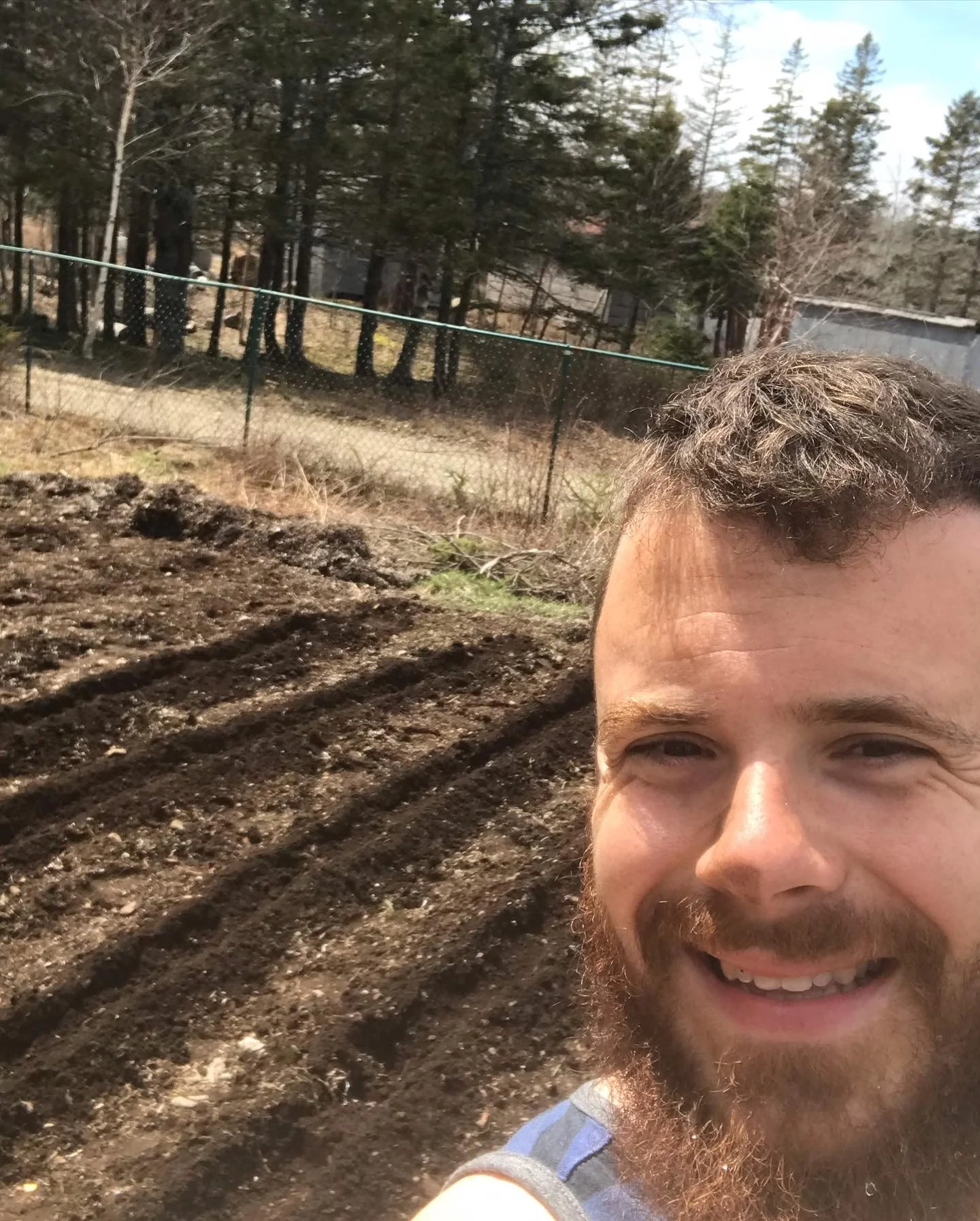 Chef Justin Andrews on a farm with garden rows behind