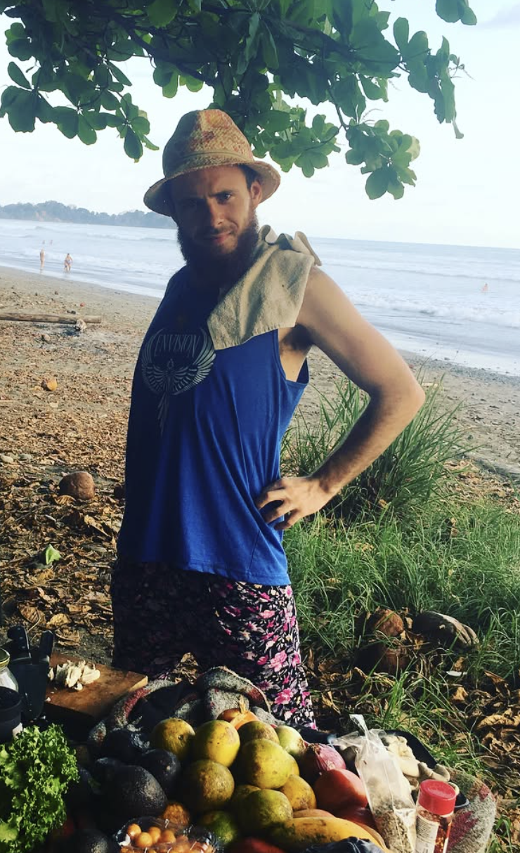 Chef Justin Andrews on a beach with a table full of fresh fruit