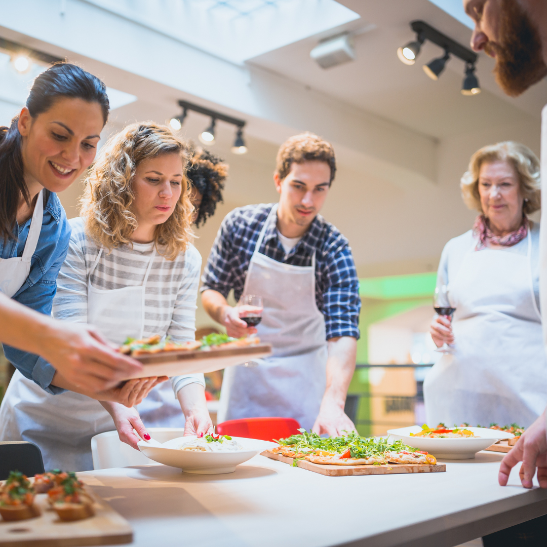 People preparing a vegetable salad with quinoa, cucumbers, carrots, and herbs in a kitchen setting.