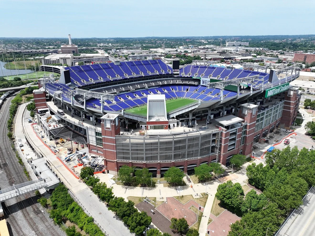 Aerial view of T-Mobile Park stadium in Seattle, Washington, with green field and blue seating, surrounded by trees and urban area.