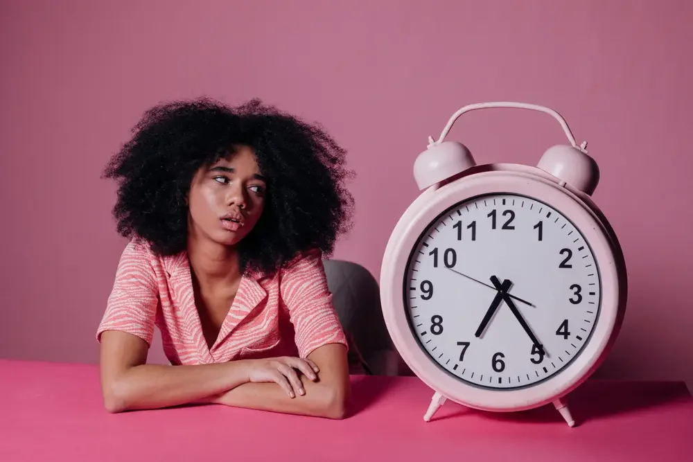 Woman looking frustrated at a large clock, representing the time it takes to rip and convert DVDs one by one at home