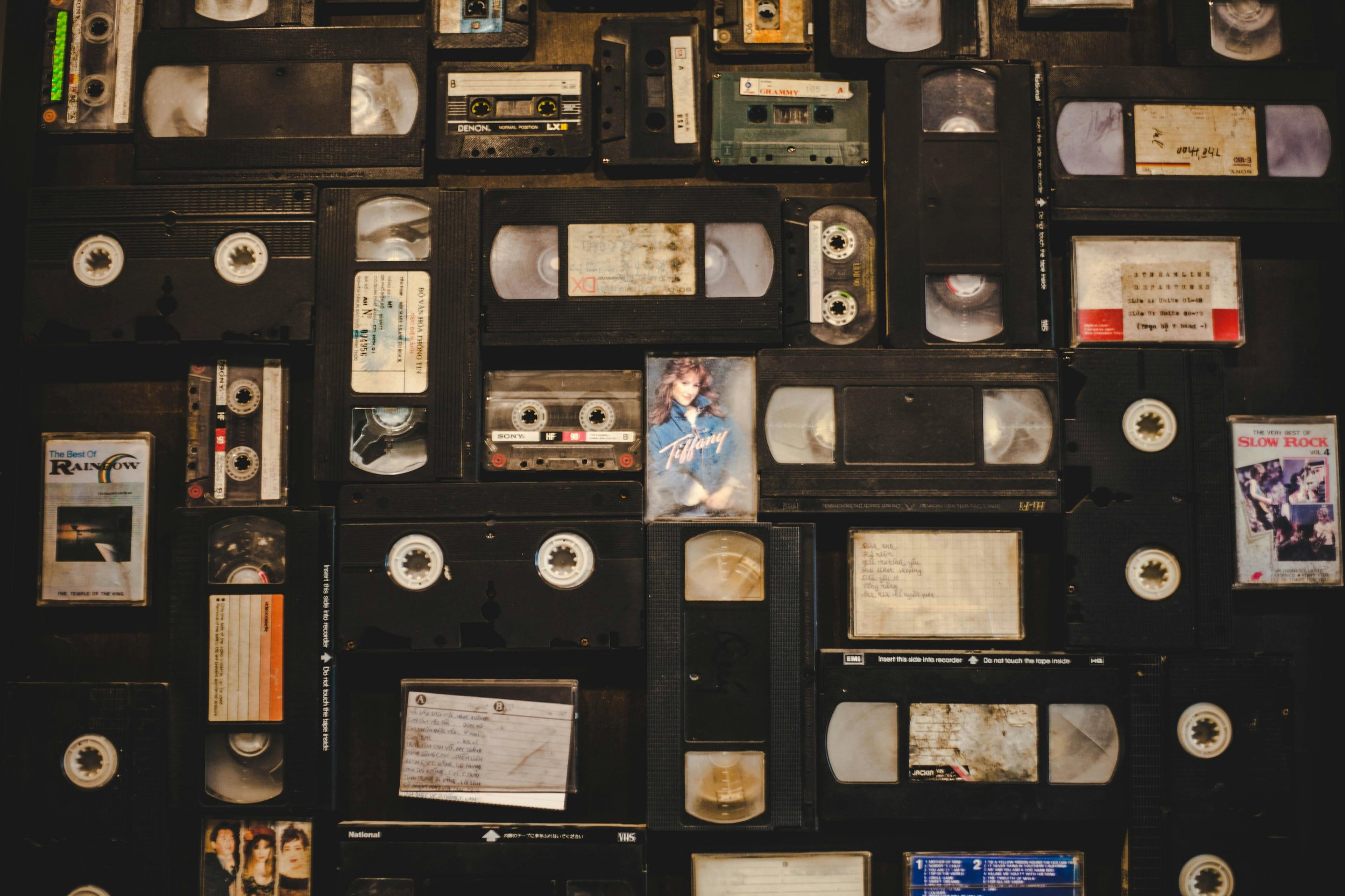 Collection of vintage video and audio cassette tapes arranged on a flat surface, personal media ready for digitization