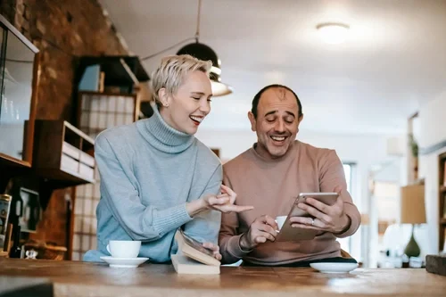 Two people, a woman and a man, sitting at a table in a cozy home