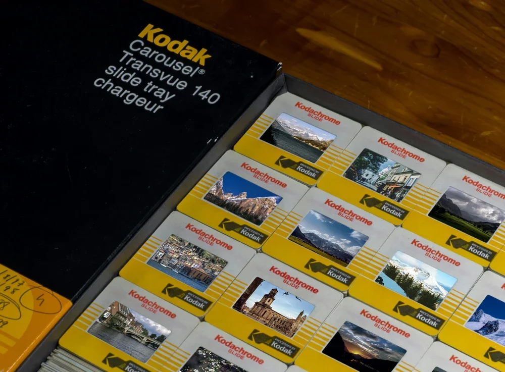 A box of Kodak Carousel slide trays with assorted photographic slides.