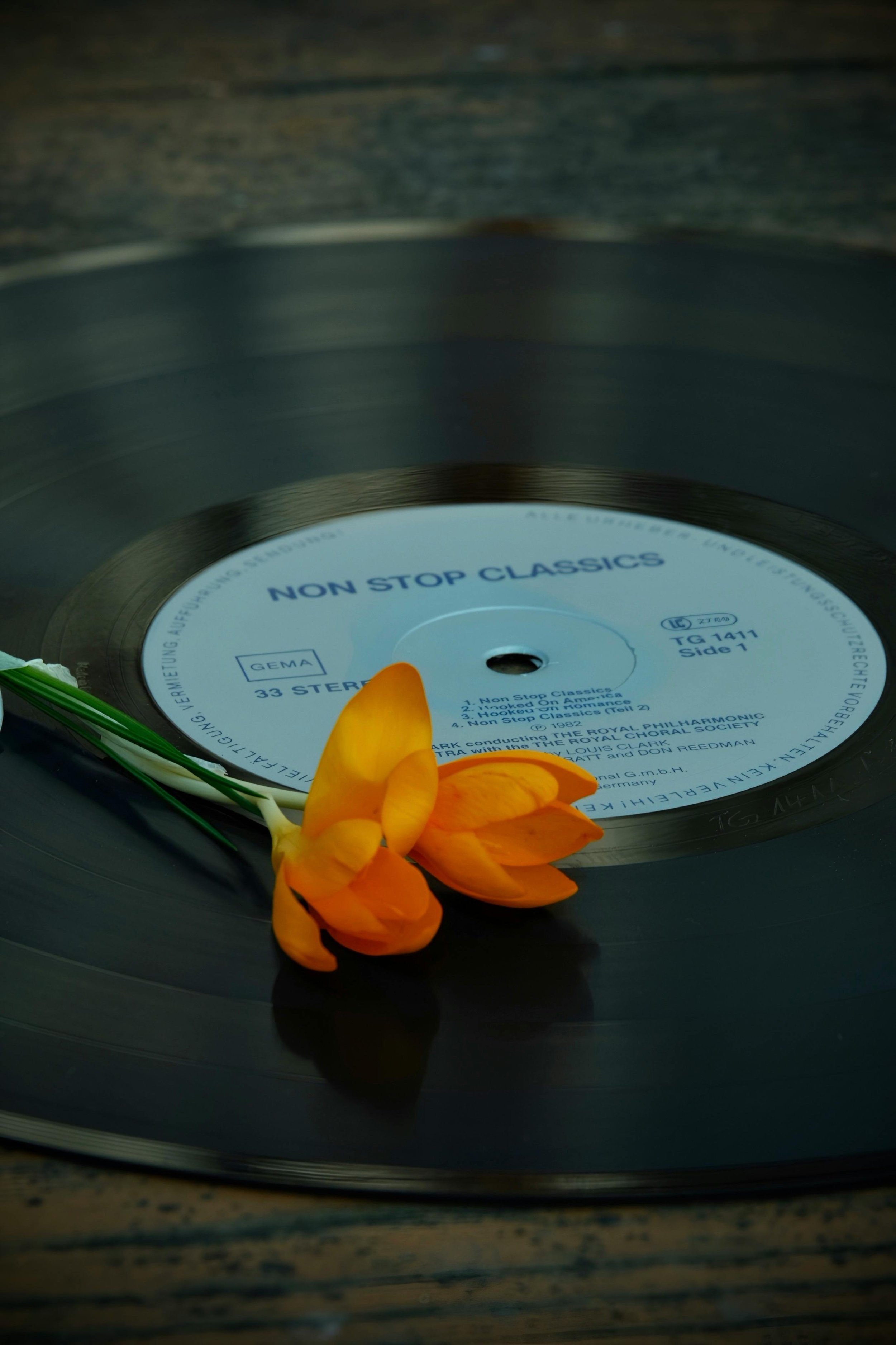 A vinyl record labeled 'Non Stop Classics' with an orange flower resting on top.
