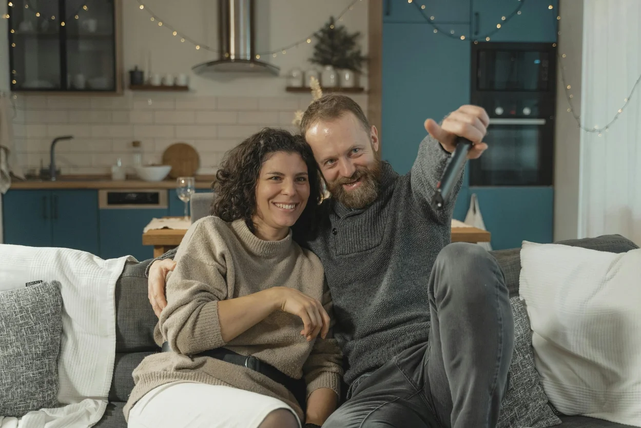 A smiling couple sitting on a couch in a cozy, decorated living room
