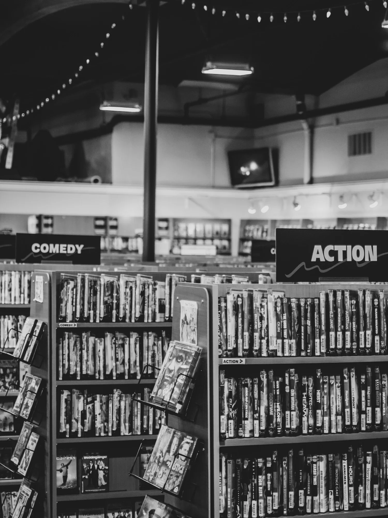 Bookshelves in a library or store categorized into 'Comedy' and 'Action' sections, with DVDs or books on display.