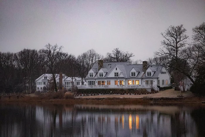 White colonial home reflected in water at dusk, a classic Fairfield County Connecticut scene