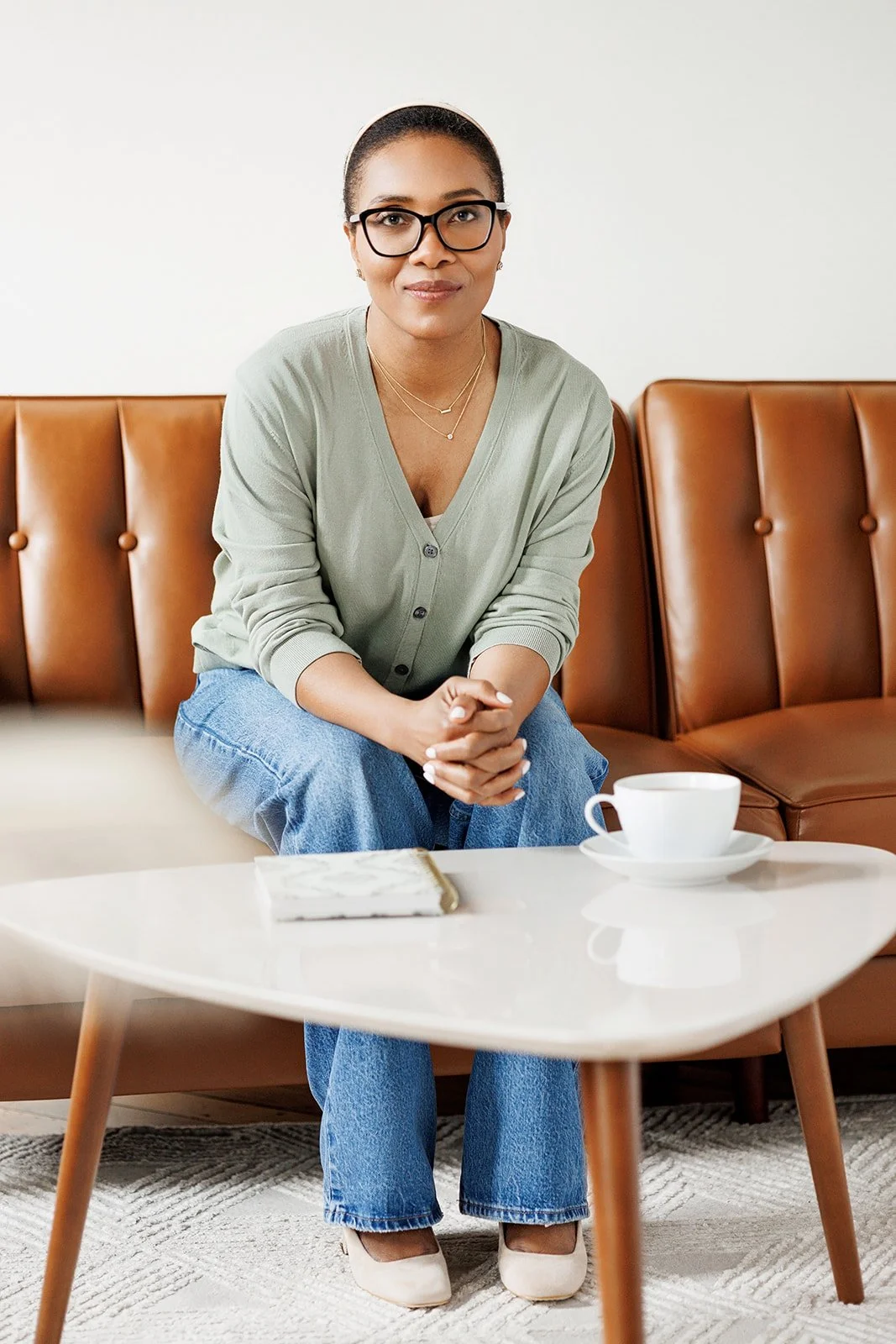 Chantal sitting on a caramel-colored couch.