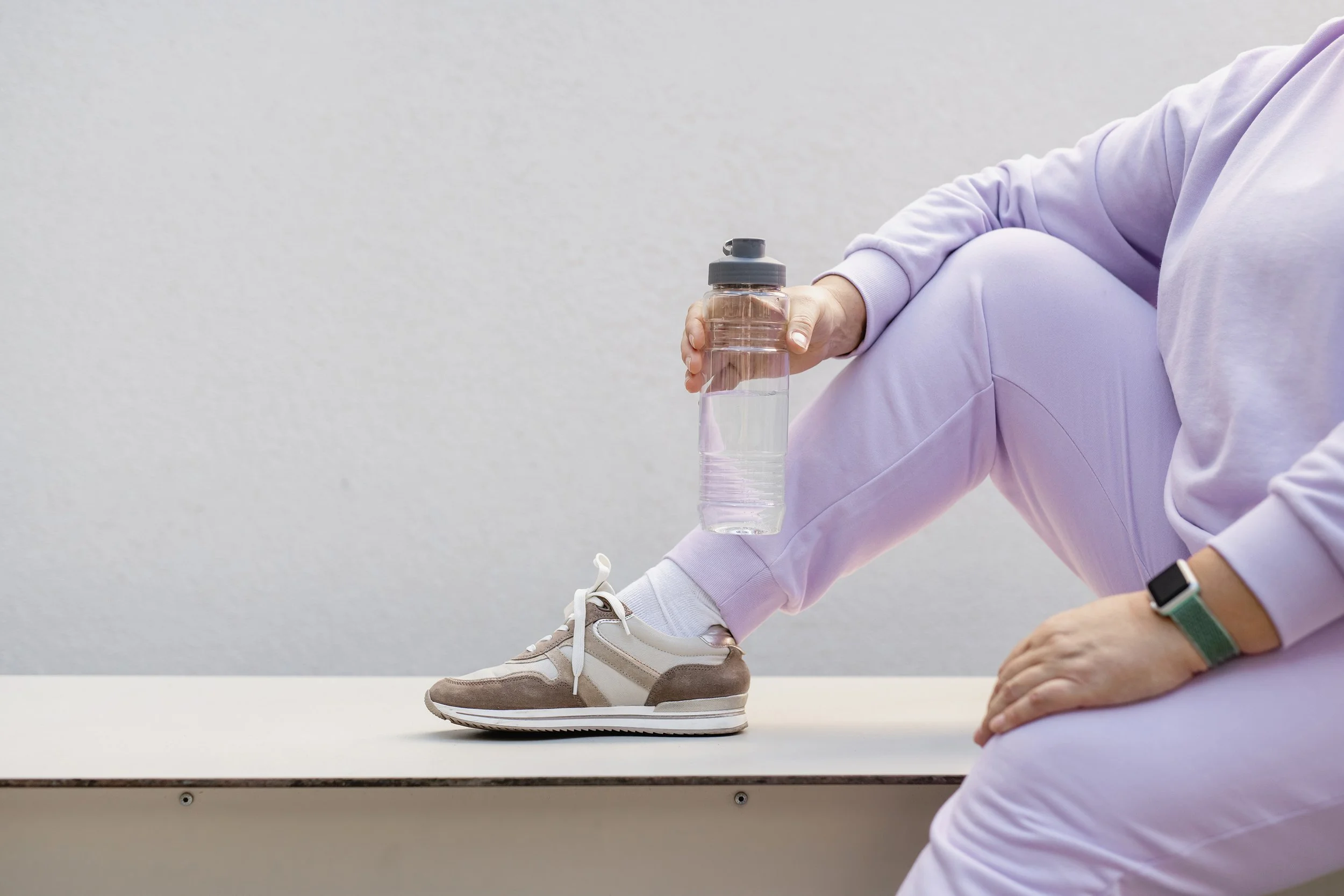 A woman in exercise clothes holding a water bottle in her hand.