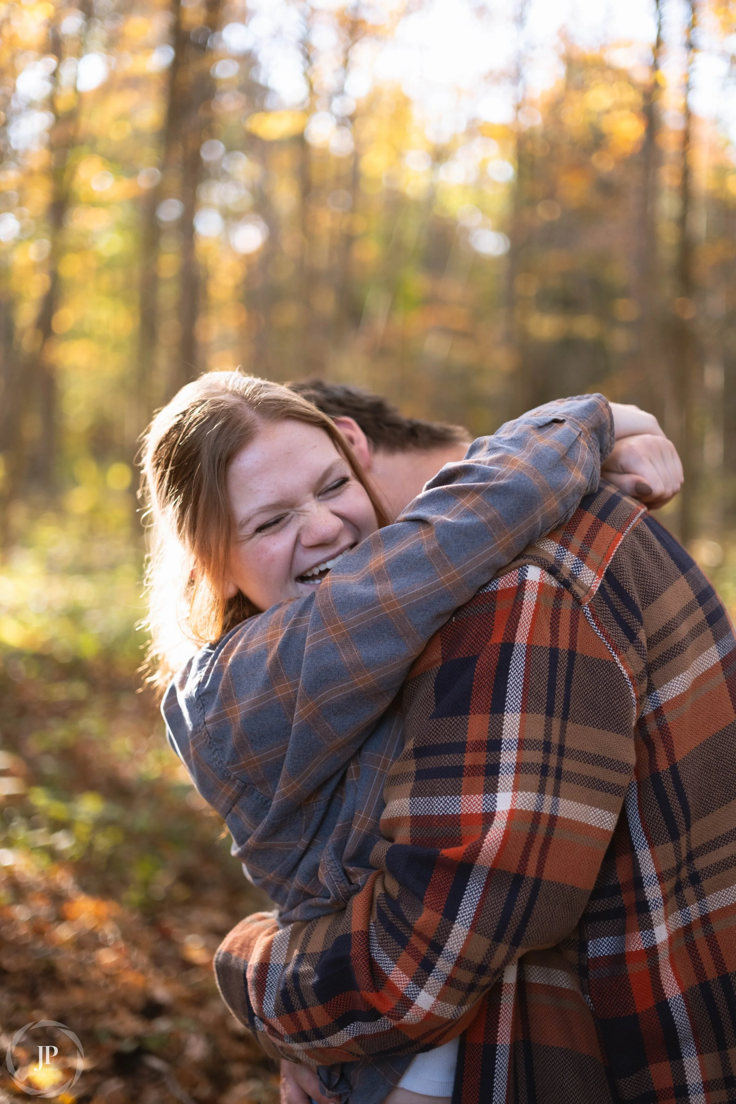 Couple hugging in autumn forest, wearing plaid shirts