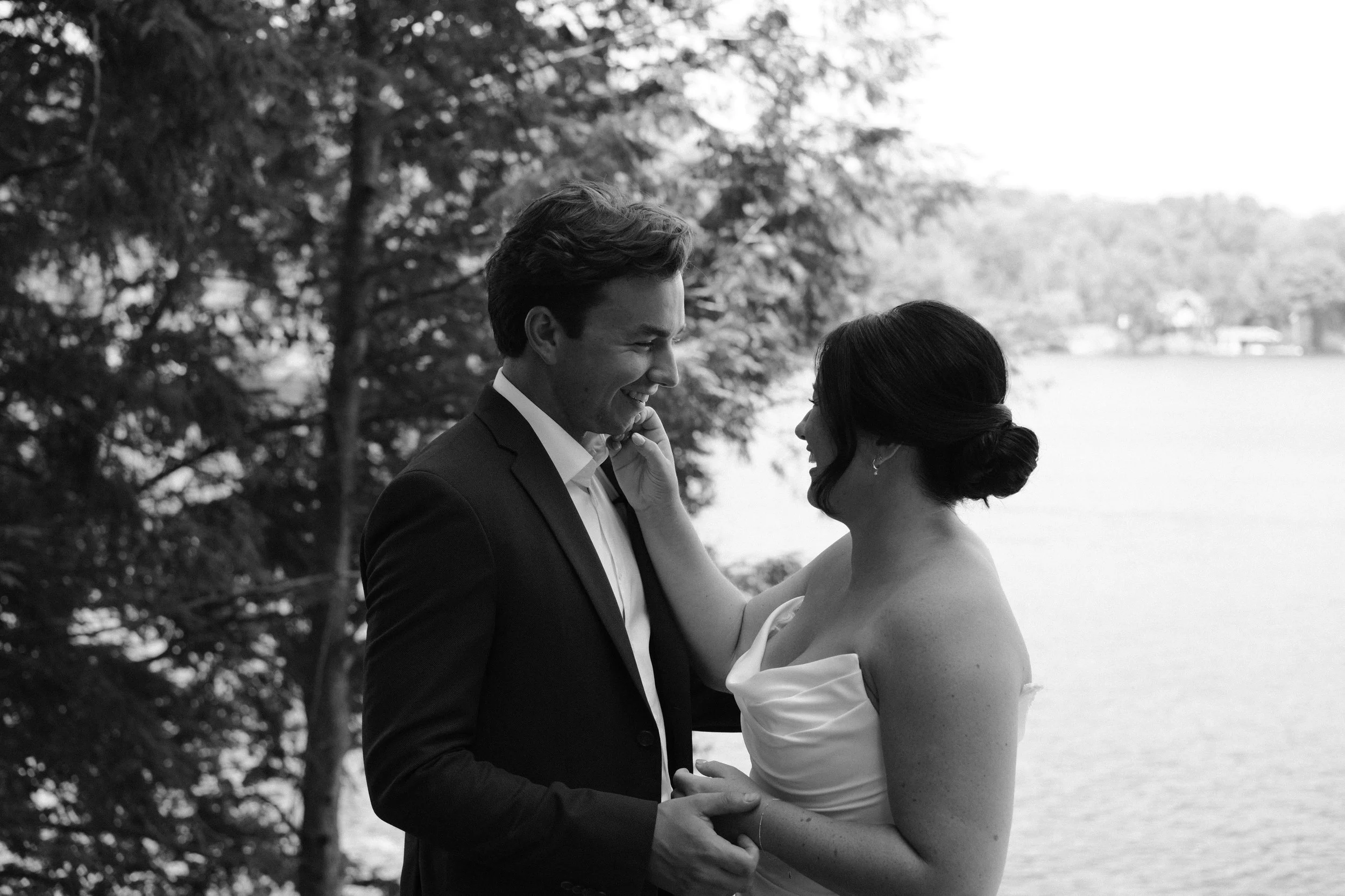 A married couple posing in black in white near a lake