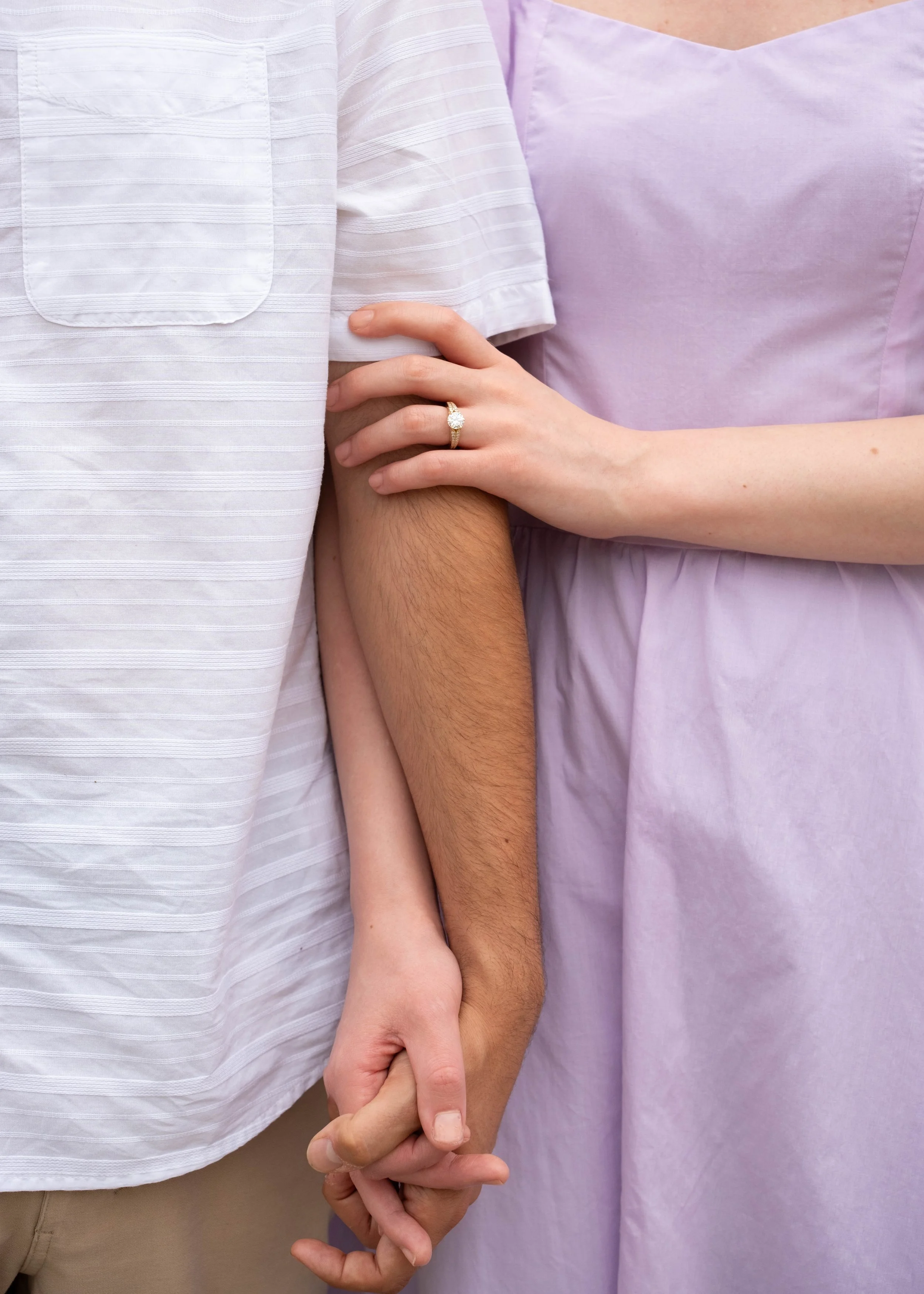 A couple holding hands showing off their engagement ring