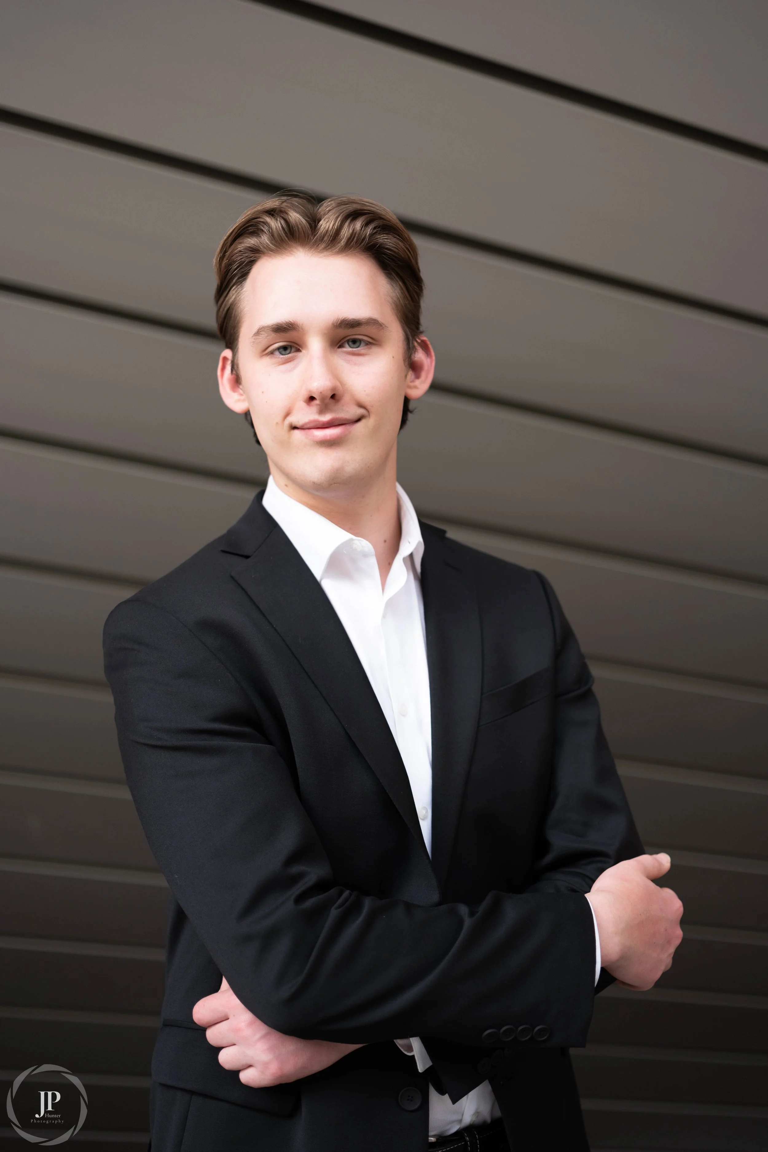 A person smiling with in a suit with a striped background