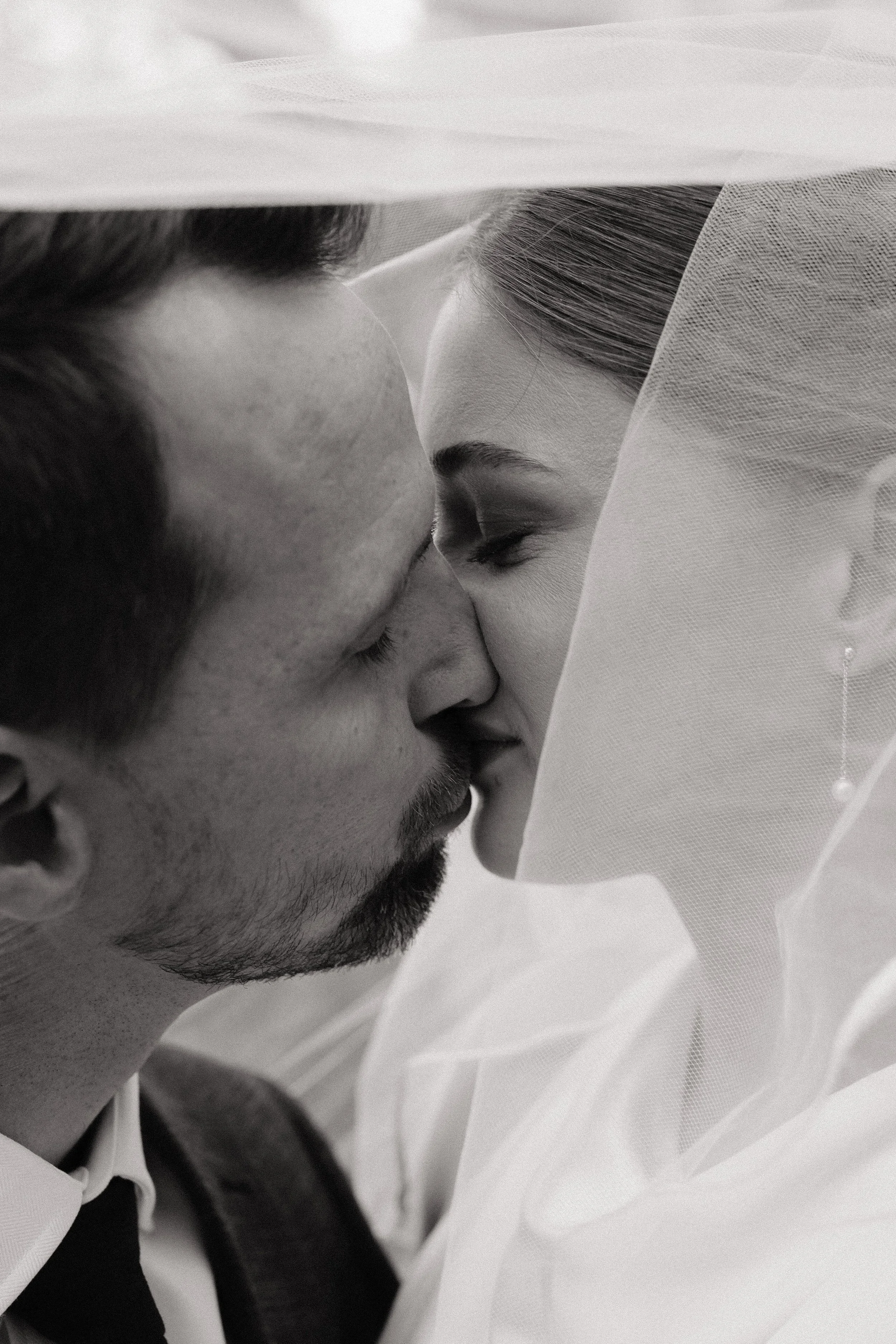A couple embrace in a kiss on their wedding day. The photograph is black and white and was captured by Adelaide Wedding Photographer, Woodley Photography