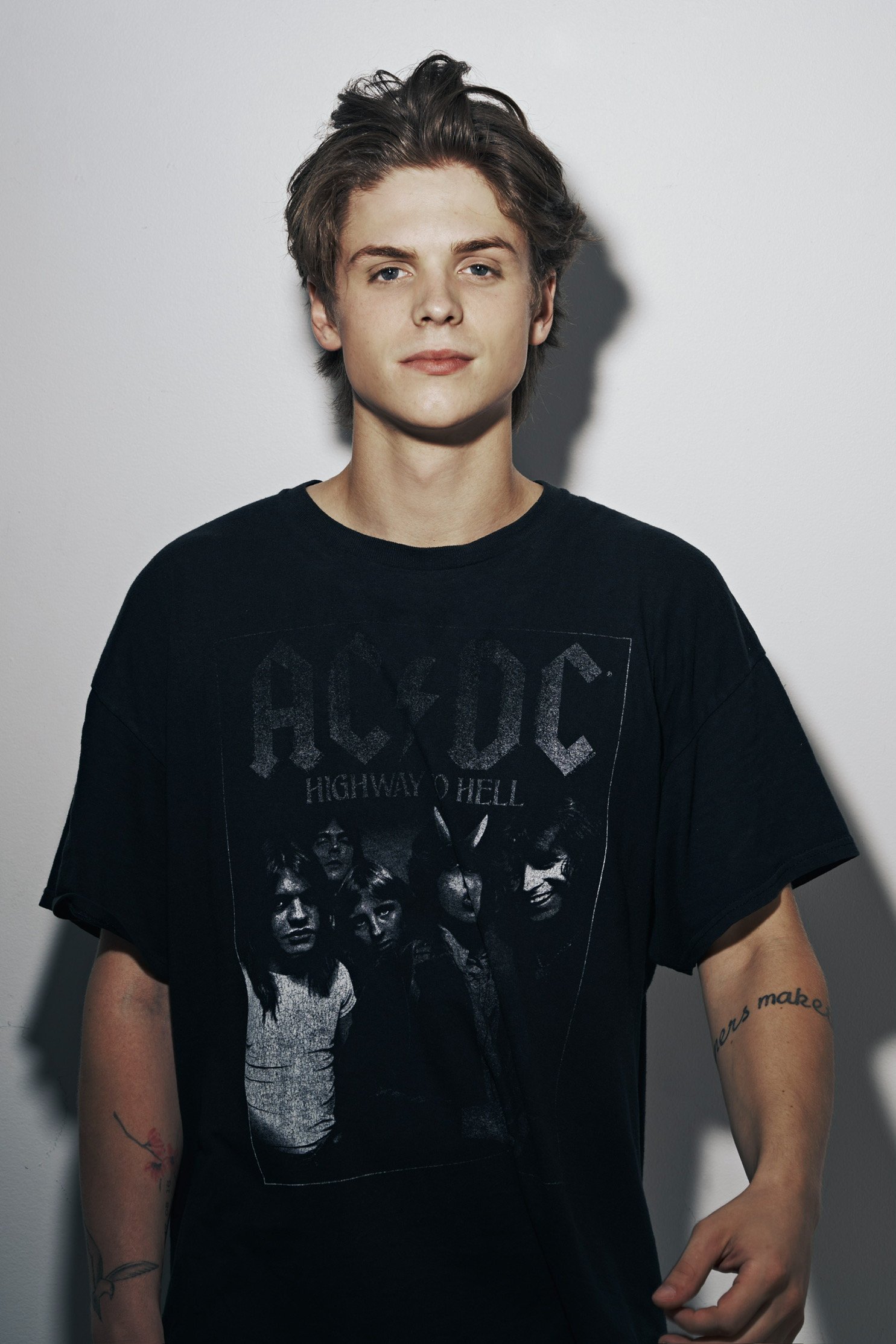 Theo Day press photo of him wearing a black AC/DC 'Highway to Hell' band t-shirt, standing against a plain wall.