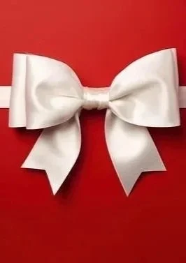 A vase with white daisies and orange marigolds, a bowl of green peas, and a glass container with yellow flowers on a wooden table, with a stone wall and framed picture in the background.