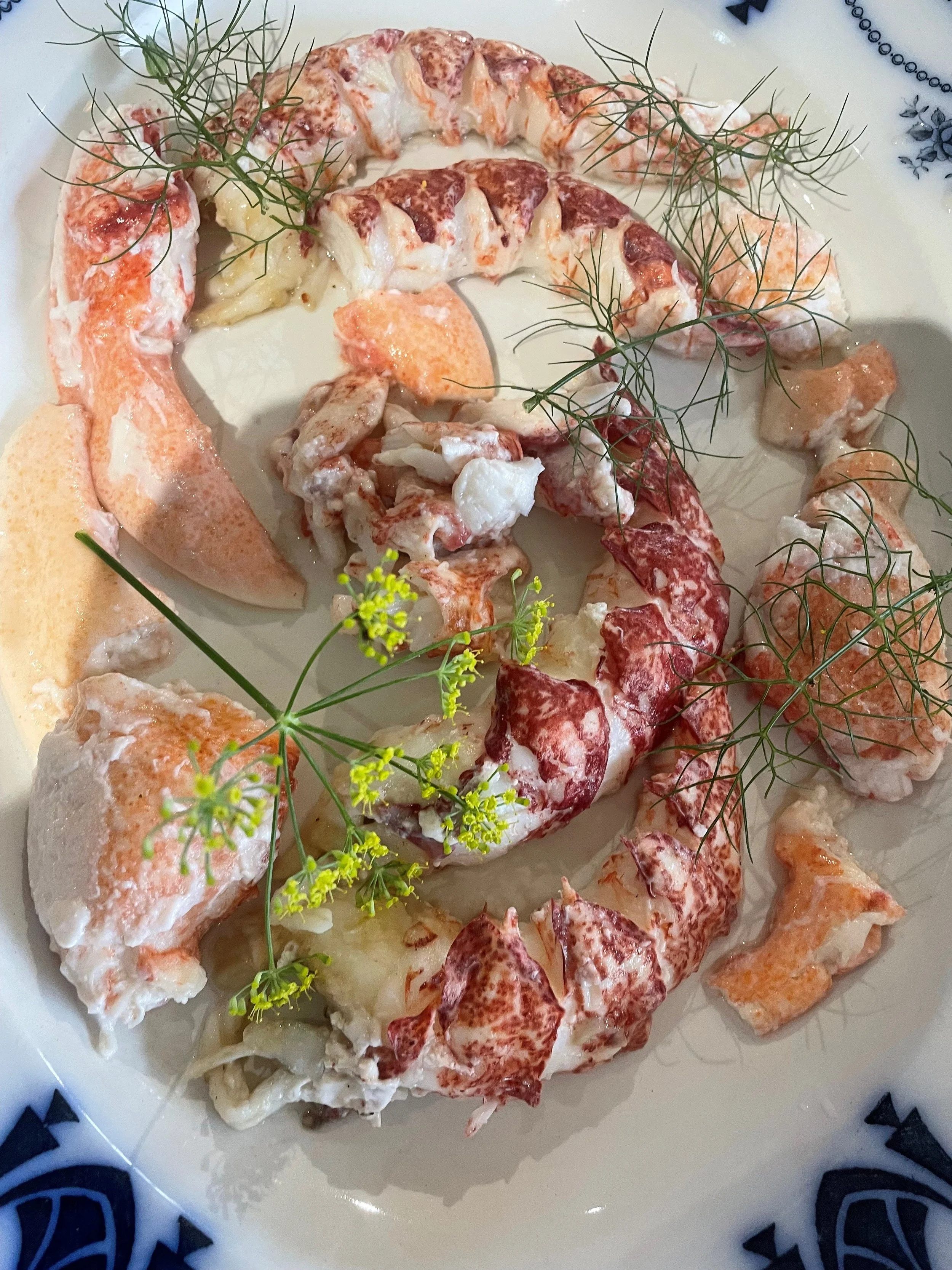 Lobster tail served on a white plate garnished with fresh herbs.