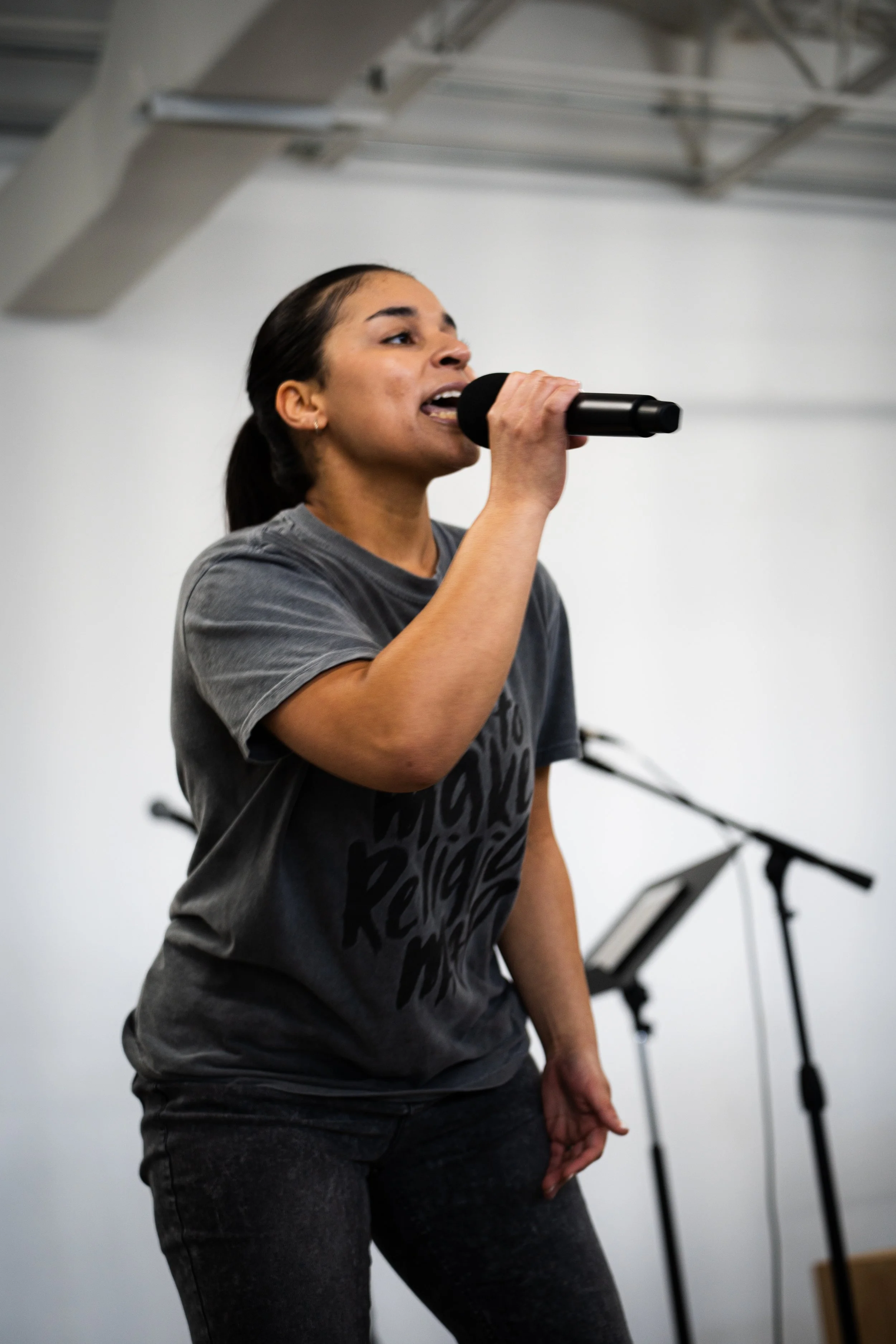 Person singing and holding a microphone, wearing a graphic t-shirt.