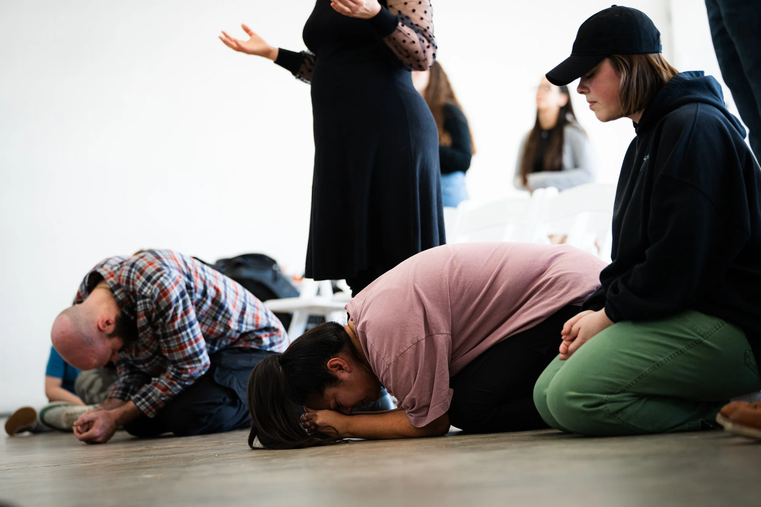 People kneeling in prayer at an indoor gathering
